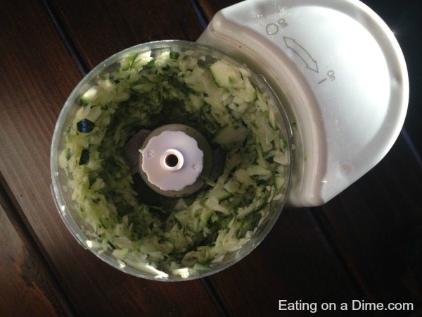 Close up image of zucchini being chopped in a food chopper. 