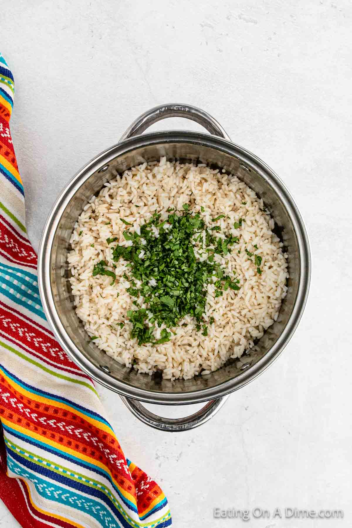 Cooked white rice in a large pan topped with fresh chopped cilantro