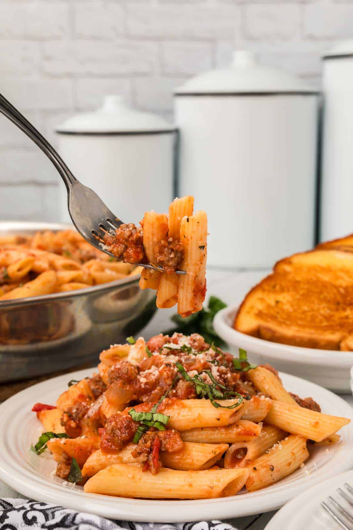 Italian Sausage pasta on a plate with a bite on a fork
