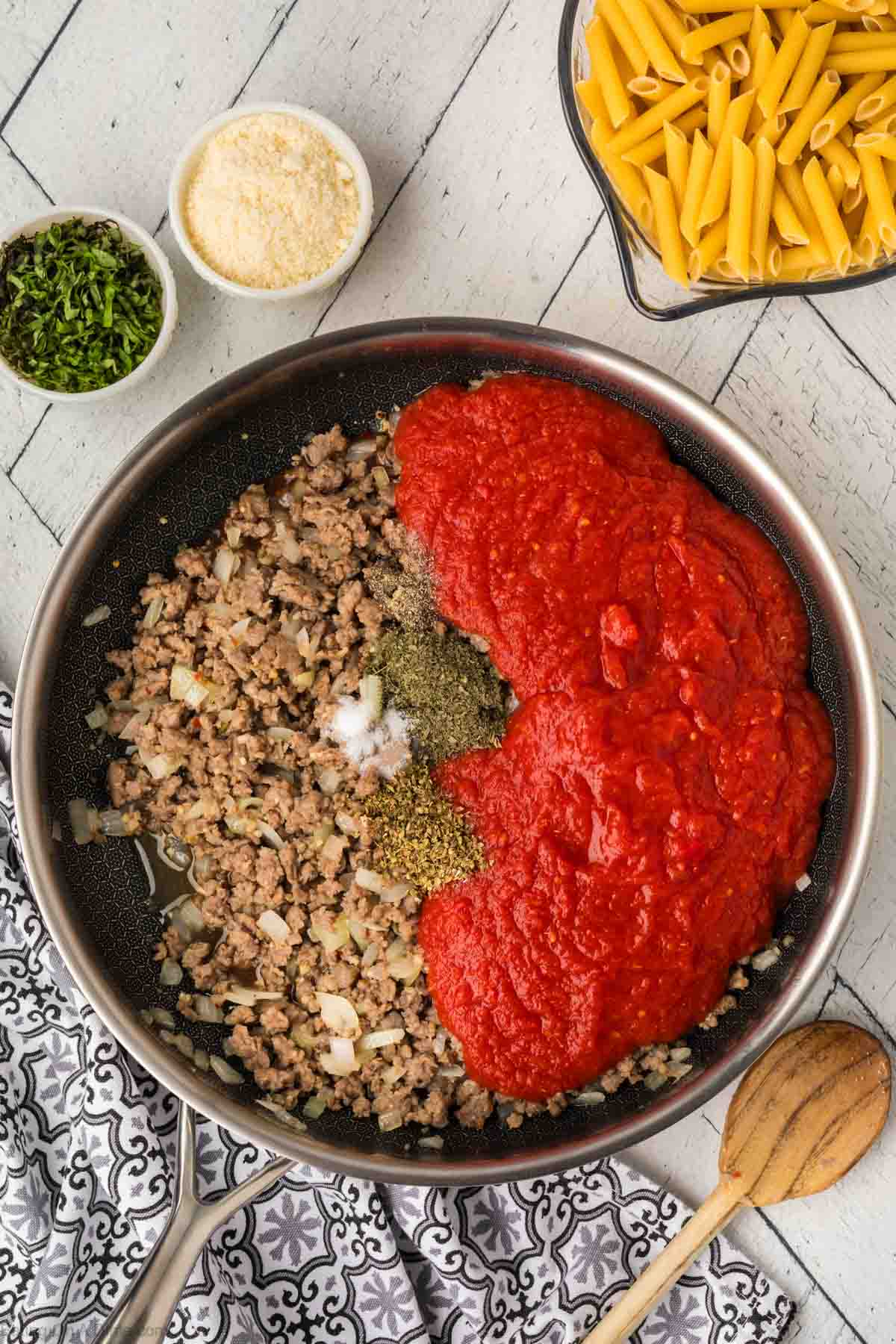 Ground beef in a skillet topped with seasoning and canned tomato sauce