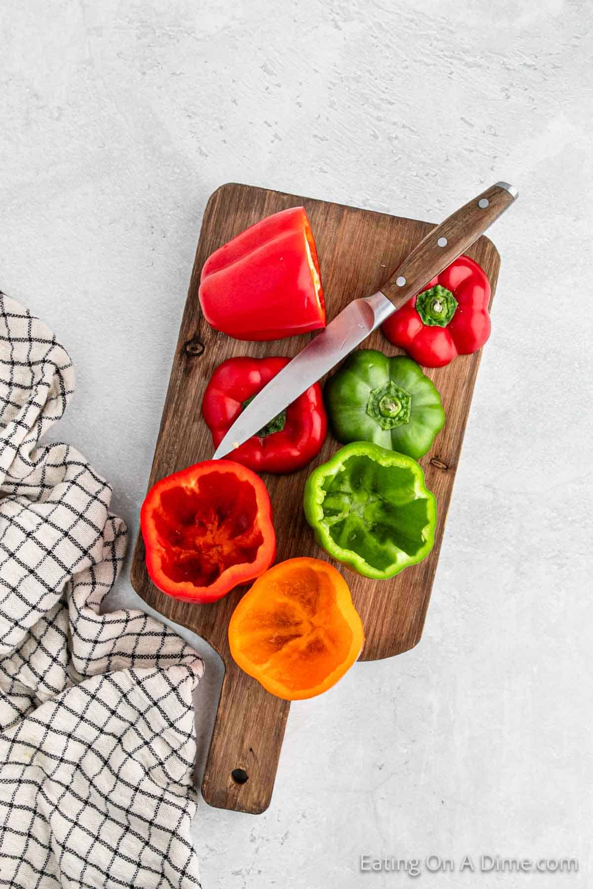 Slice the tops off the bell peppers on a cutting board with a knife