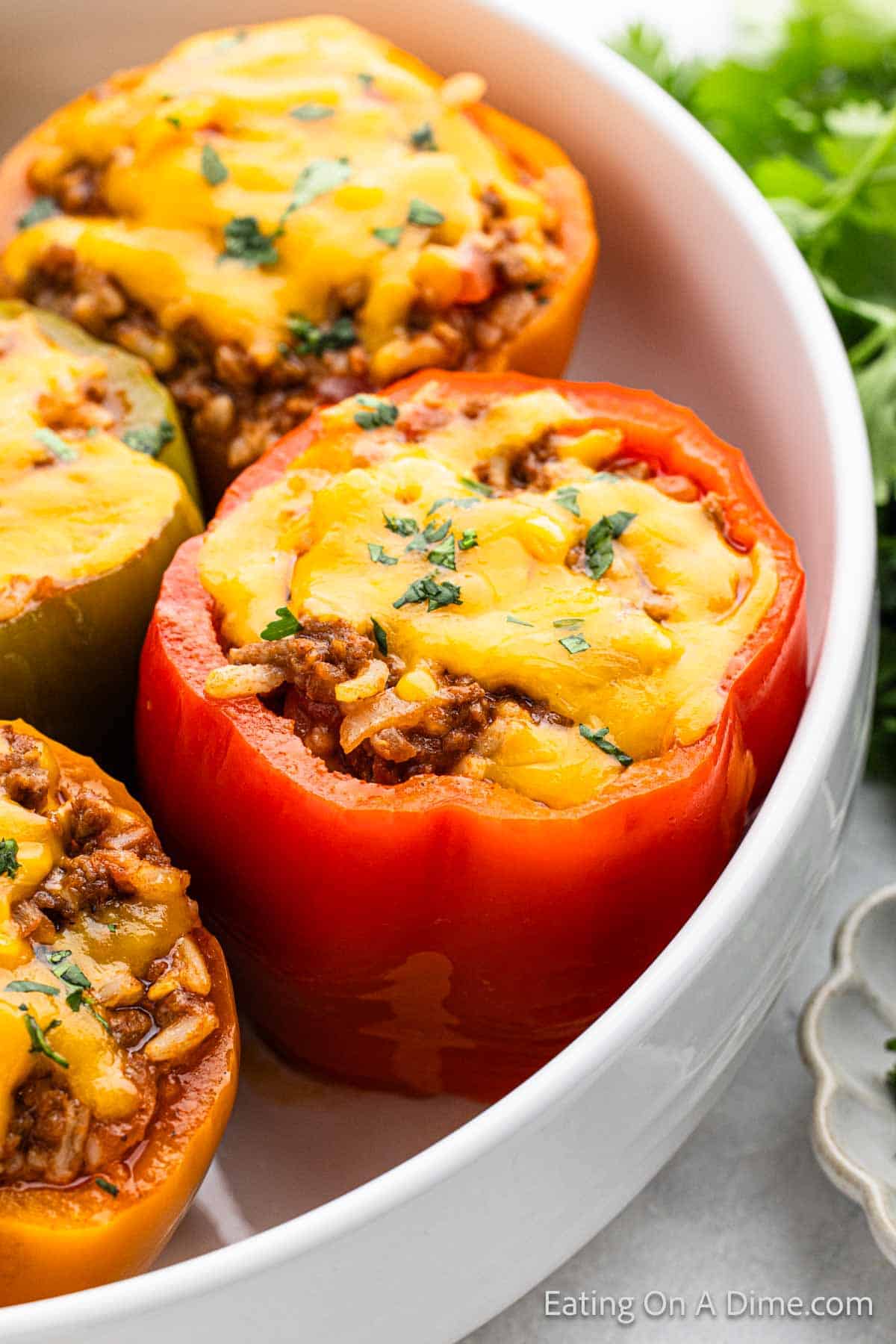Stuffed Peppers in a white dish topped with melted cheese 