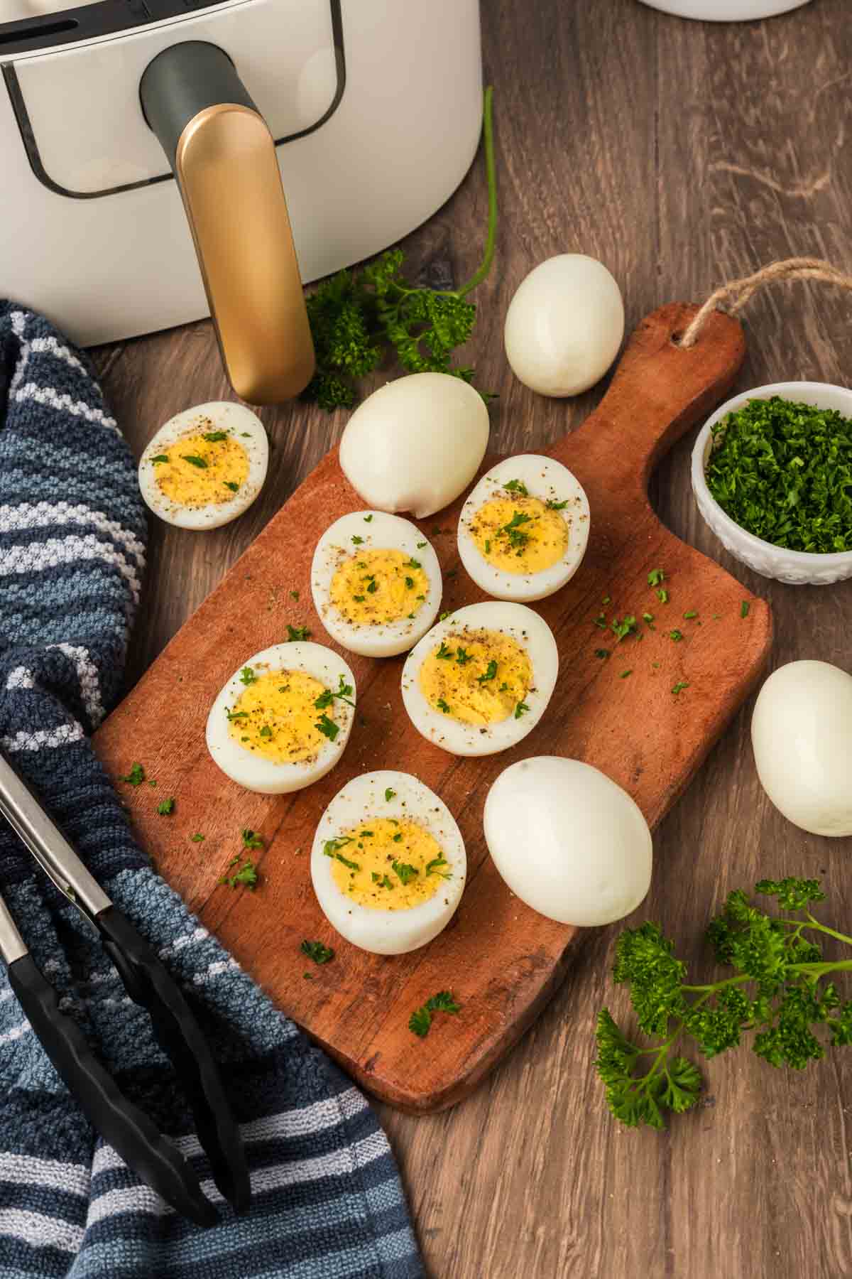 hard boiled eggs cut in half on a cutting board topped with seasoning and fresh herbs. 
