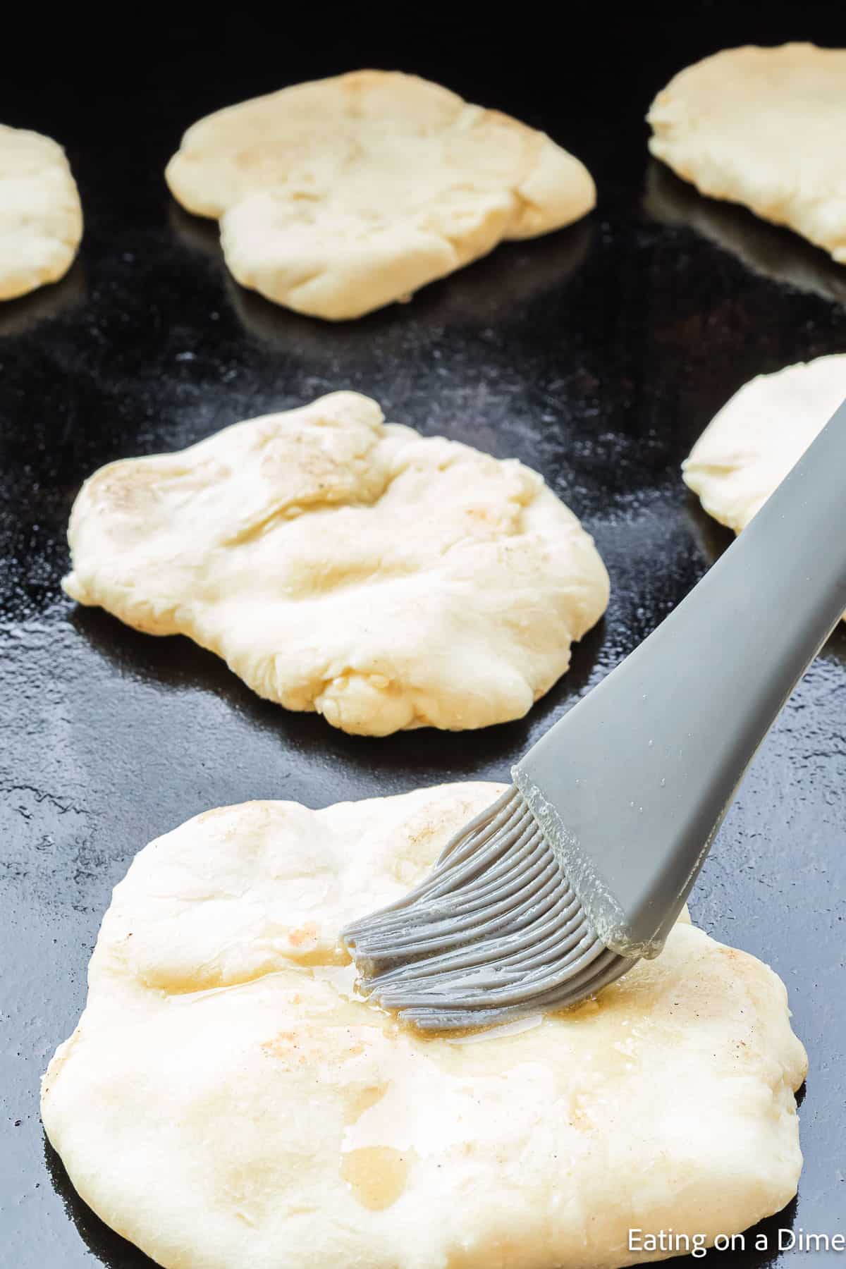 Brushing butter on the dough on the grill