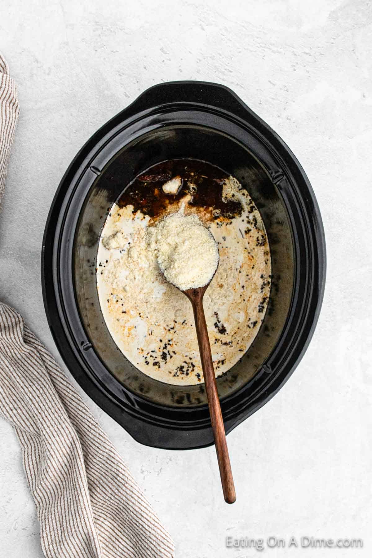 Heavy cream and shredded parmesan cheese mixed in with the broth in the slow cooker with a wooden spoon