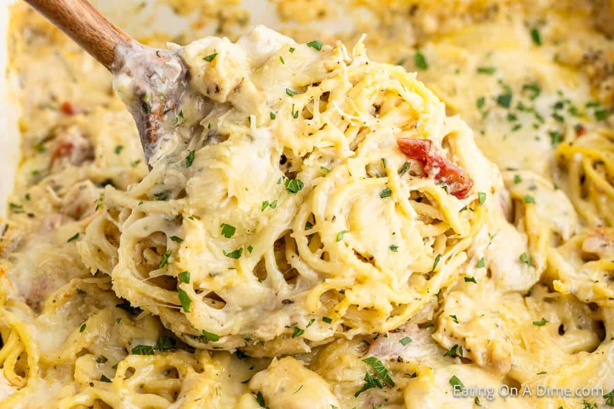 Chicken spaghetti casserole with a serving on a wooden spoon