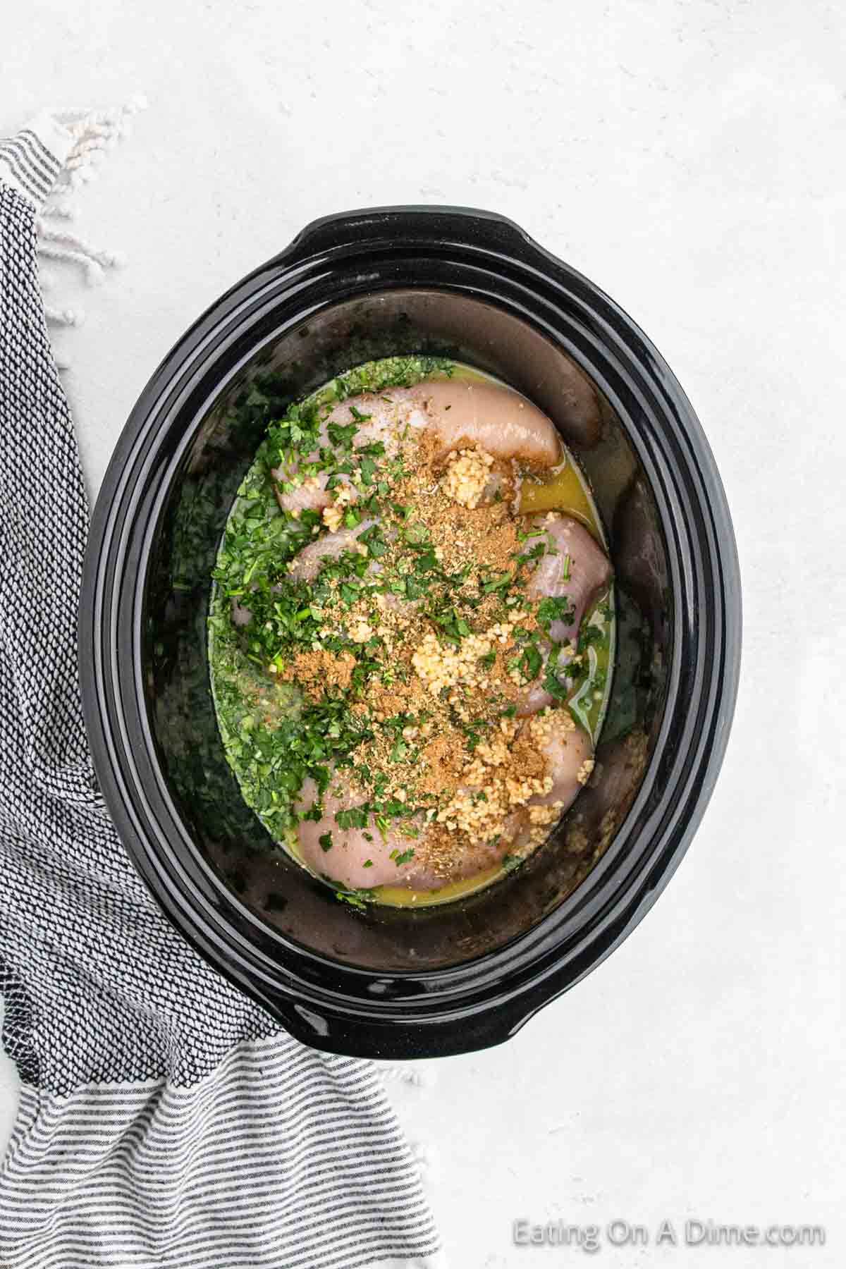 Placing the chicken, orange juice, fresh cilantro, seasoning and minced garlic in the slow cooker