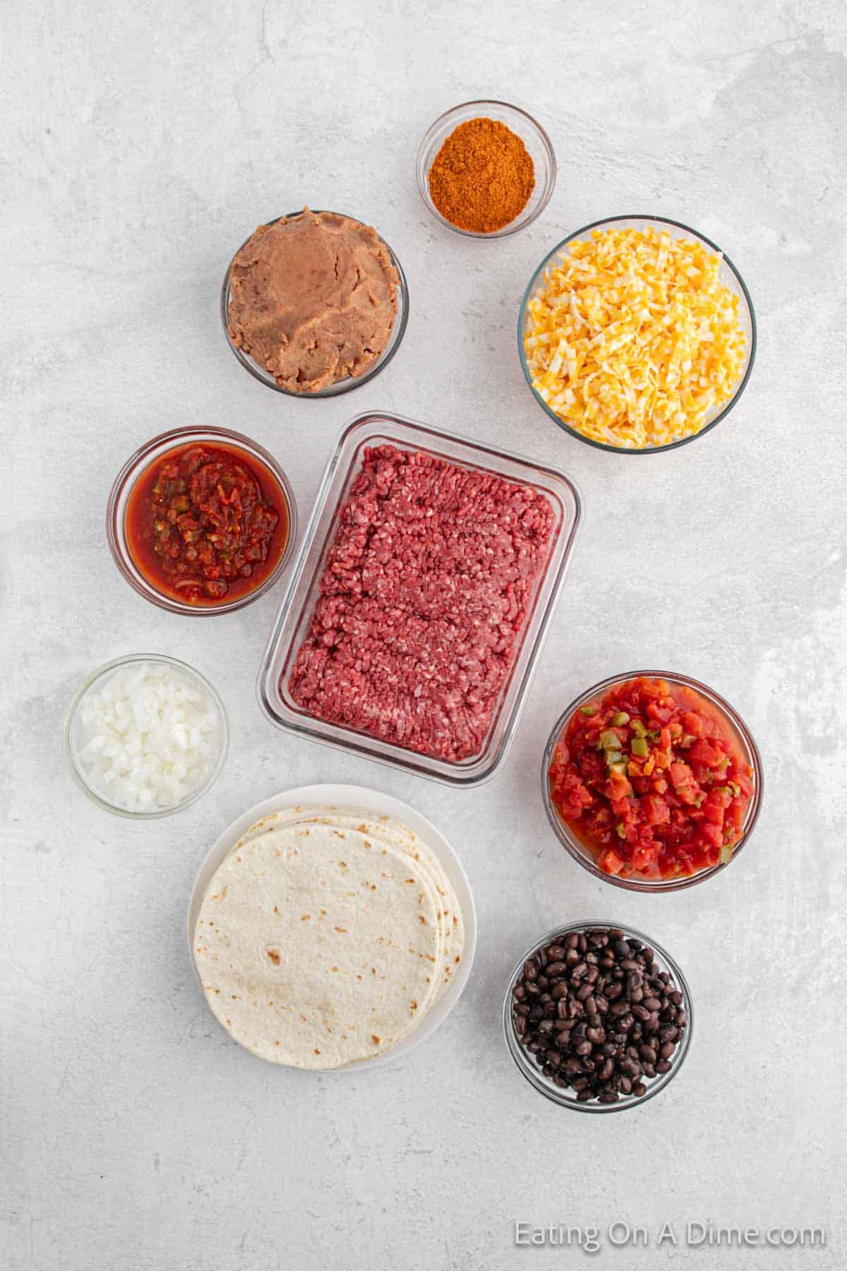 Ingredients - Ground beef, white onion, taco seasoning, salsa, black beans, diced tomatoes with green chiles, refried beans, flour tortillas, cheese