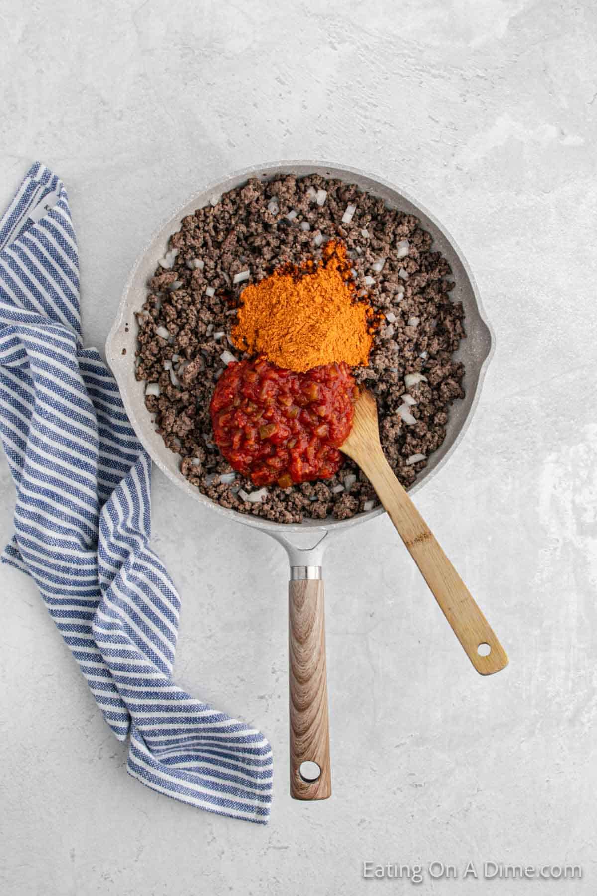 Cooked ground beef in a skillet with salsa and taco seasoning