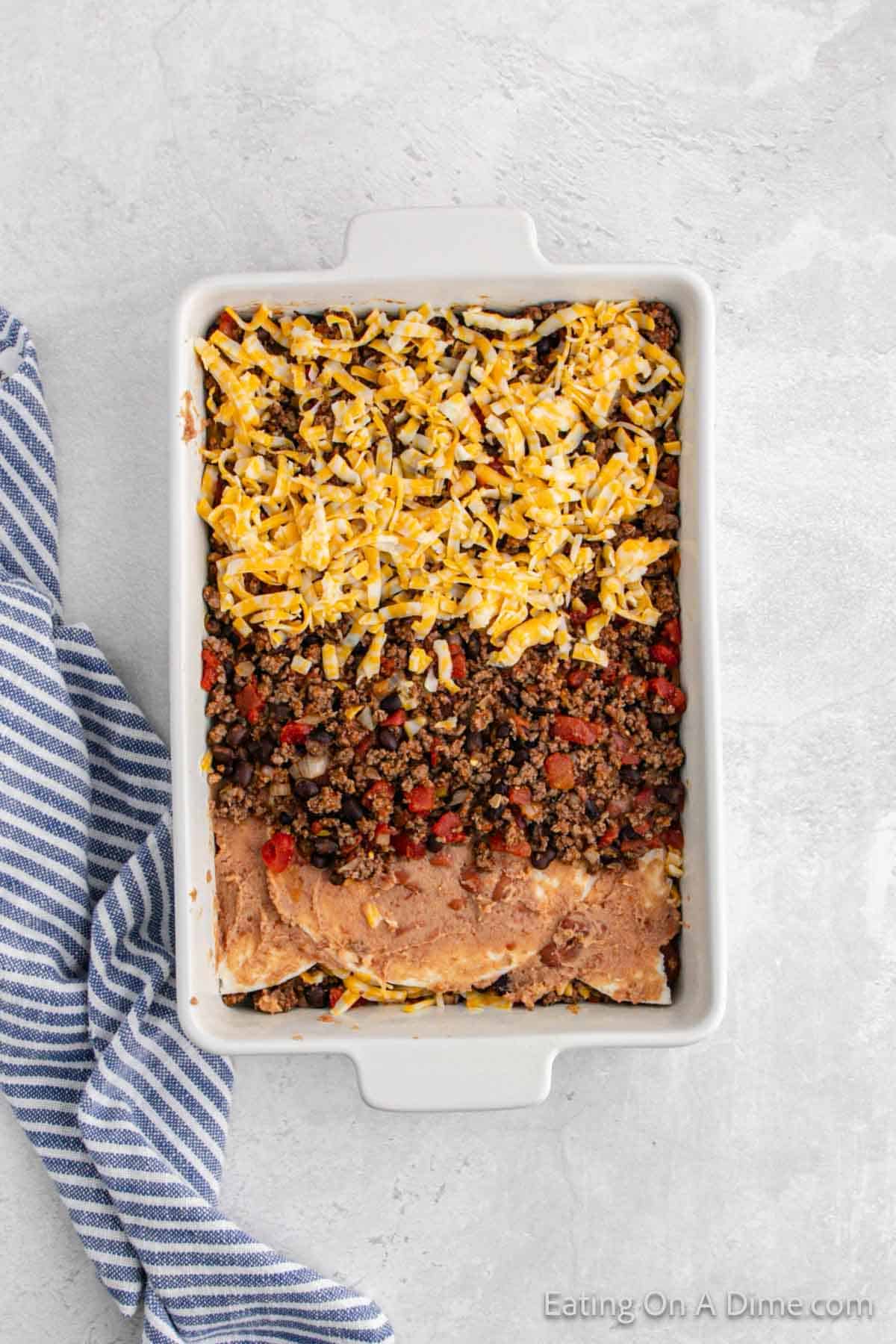 Flour tortilla, refried beans, ground beef mixture, shredded cheese layered in baking dish