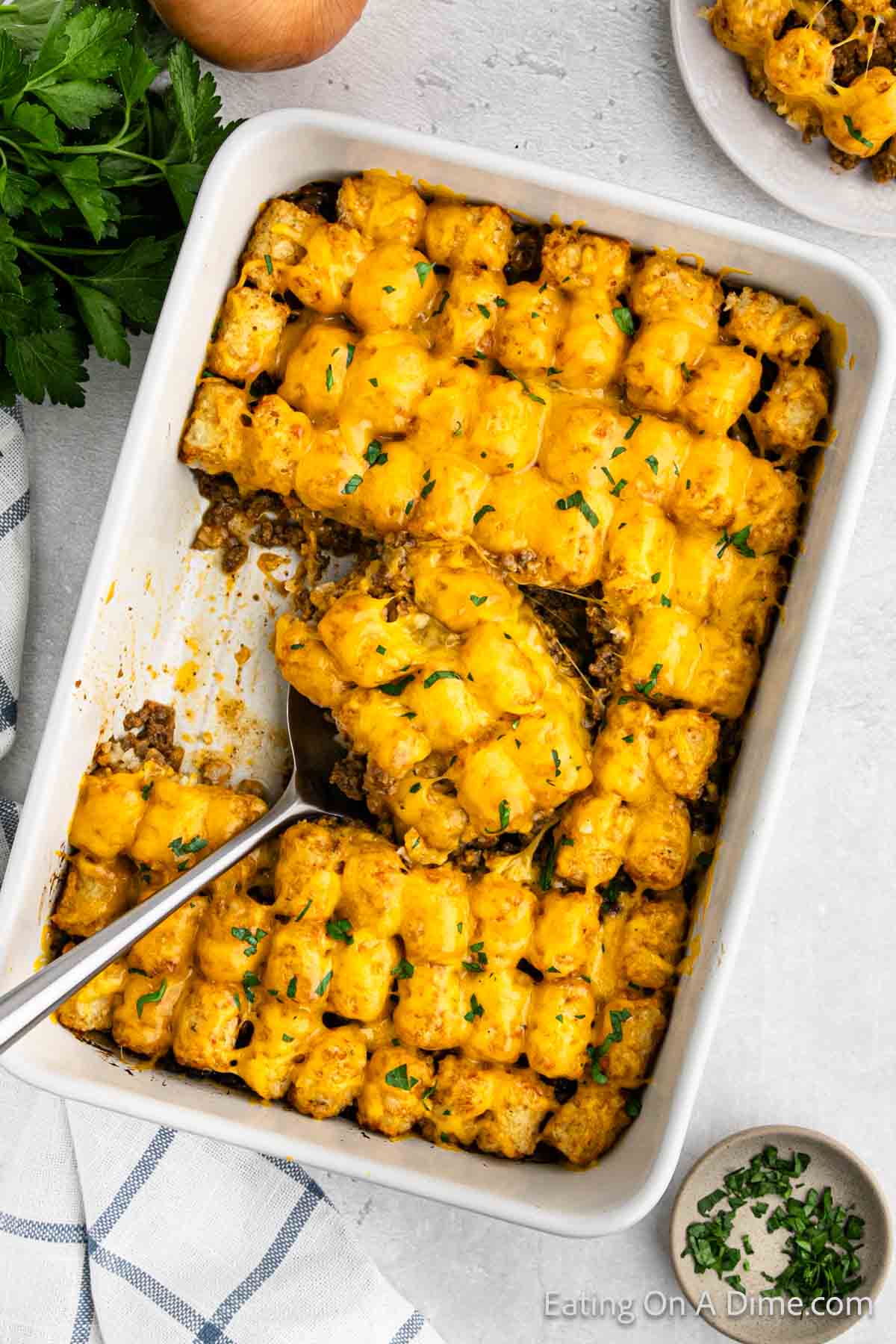 Cheeseburger tator tot casserole in a baking dish with a serving on the spatula
