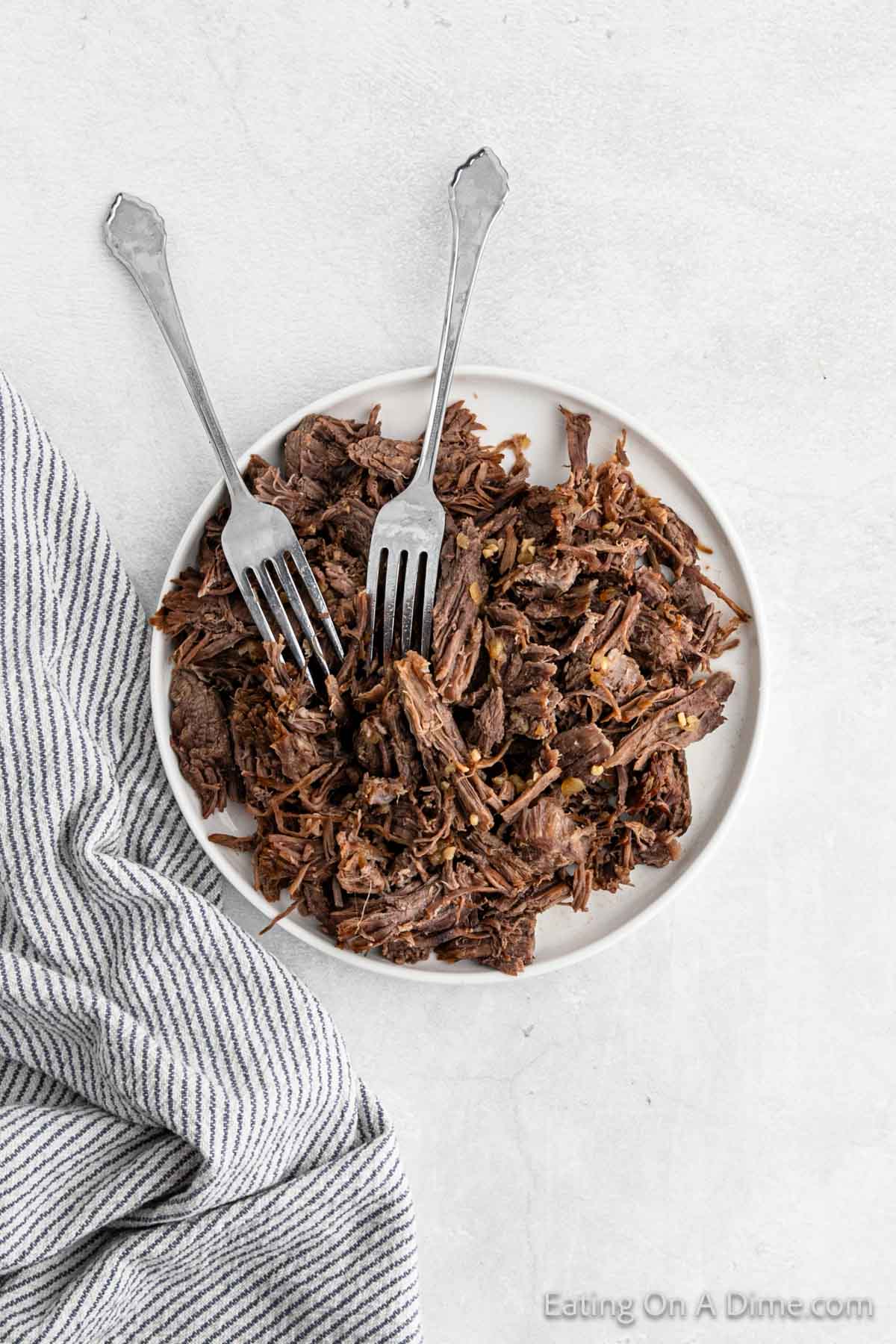 Shredded beef on a plate with two forks