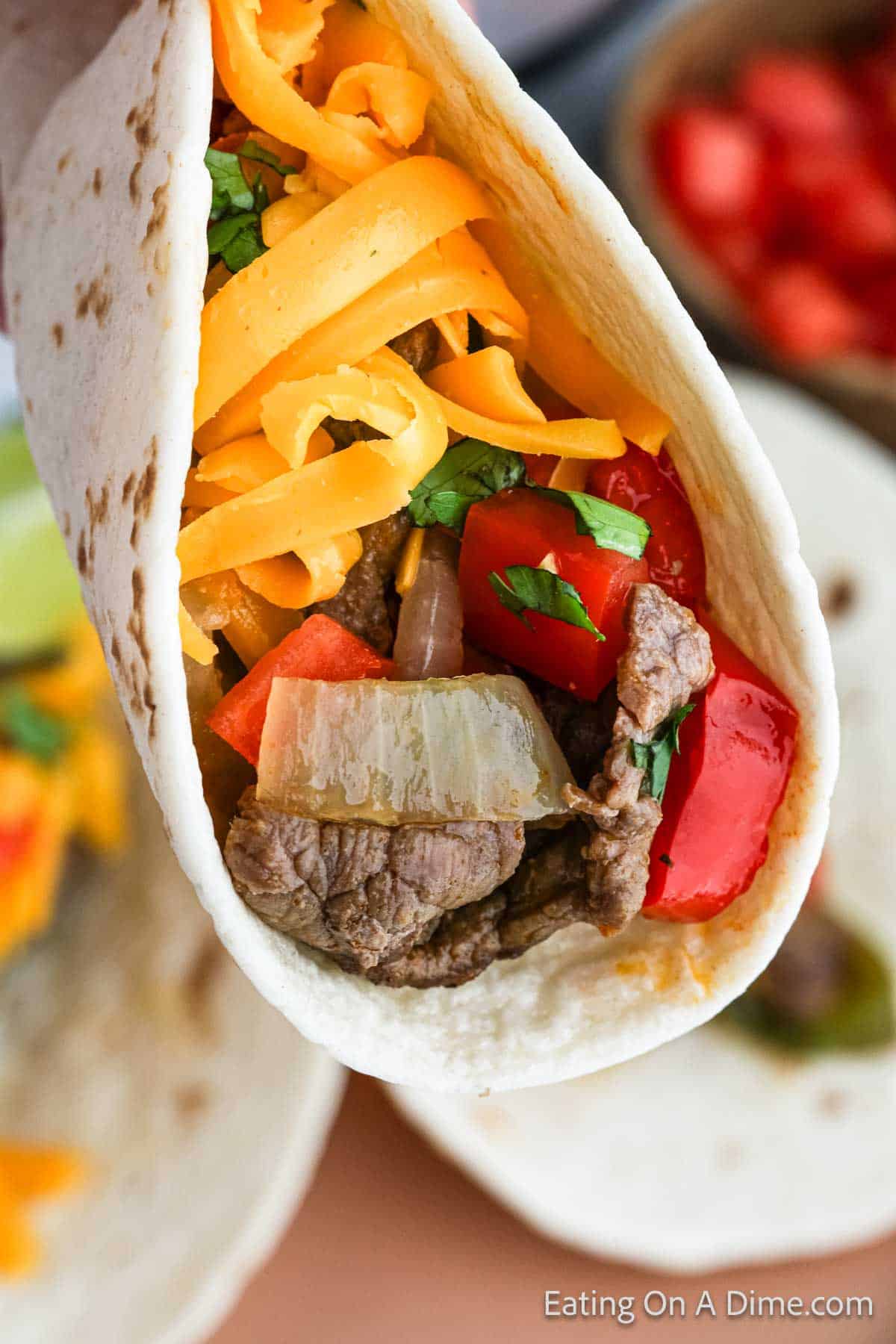 Steak fajitas with shredded cheese wrapped in a flour tortilla