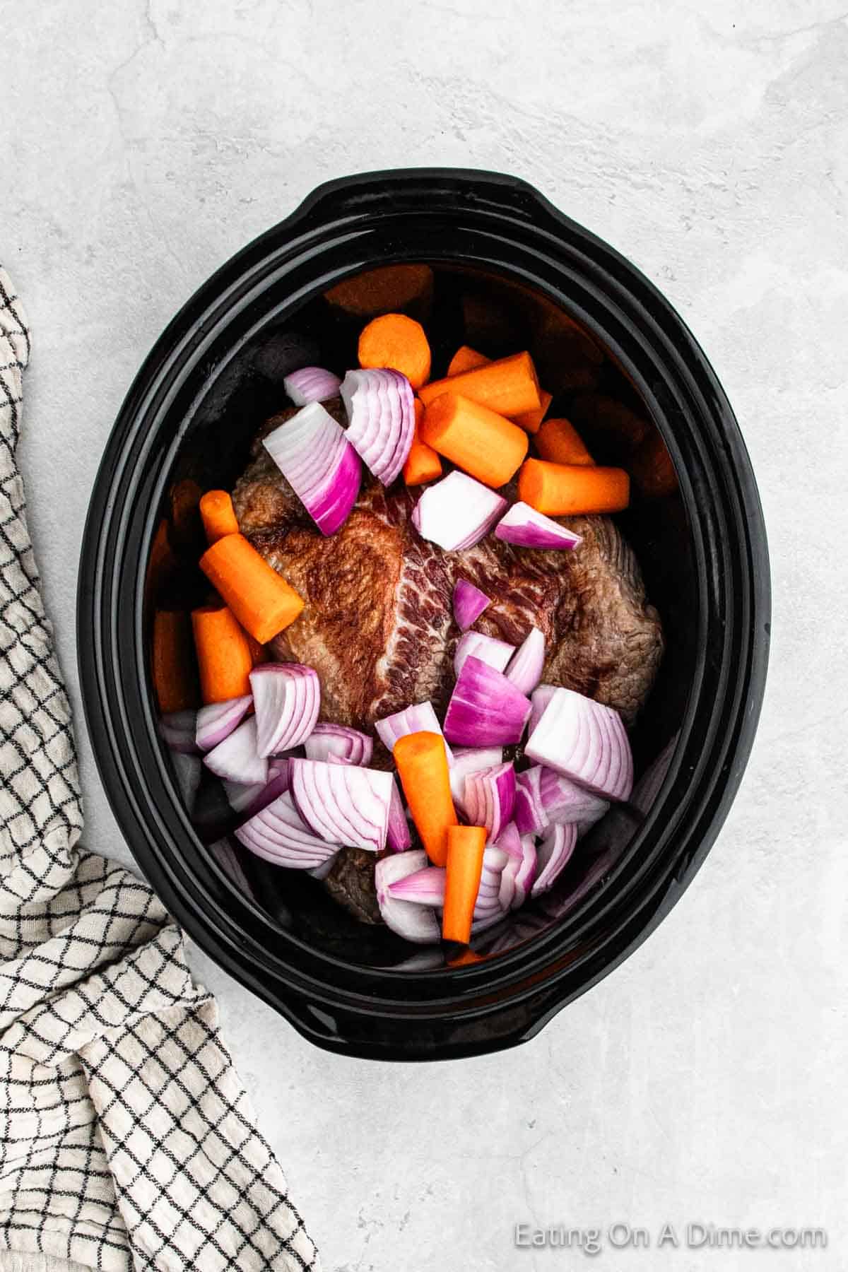 Brisket in a slow cooker with carrots and red onion