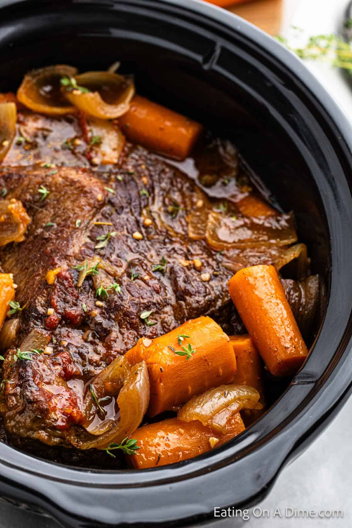 Brisket in a slow cooker topped with cooked carrots