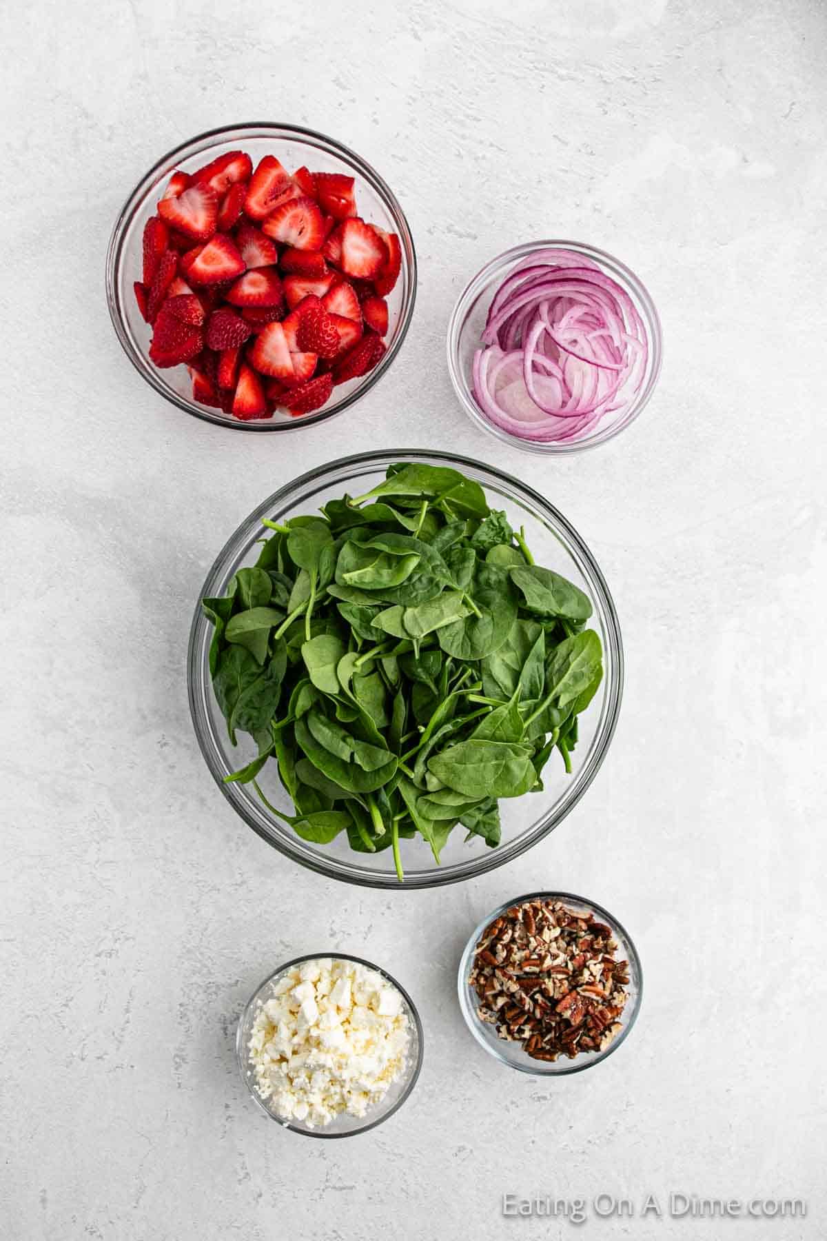 Slice strawberries, fresh spinach, red onions, chopped pecans and blue cheese crumbles