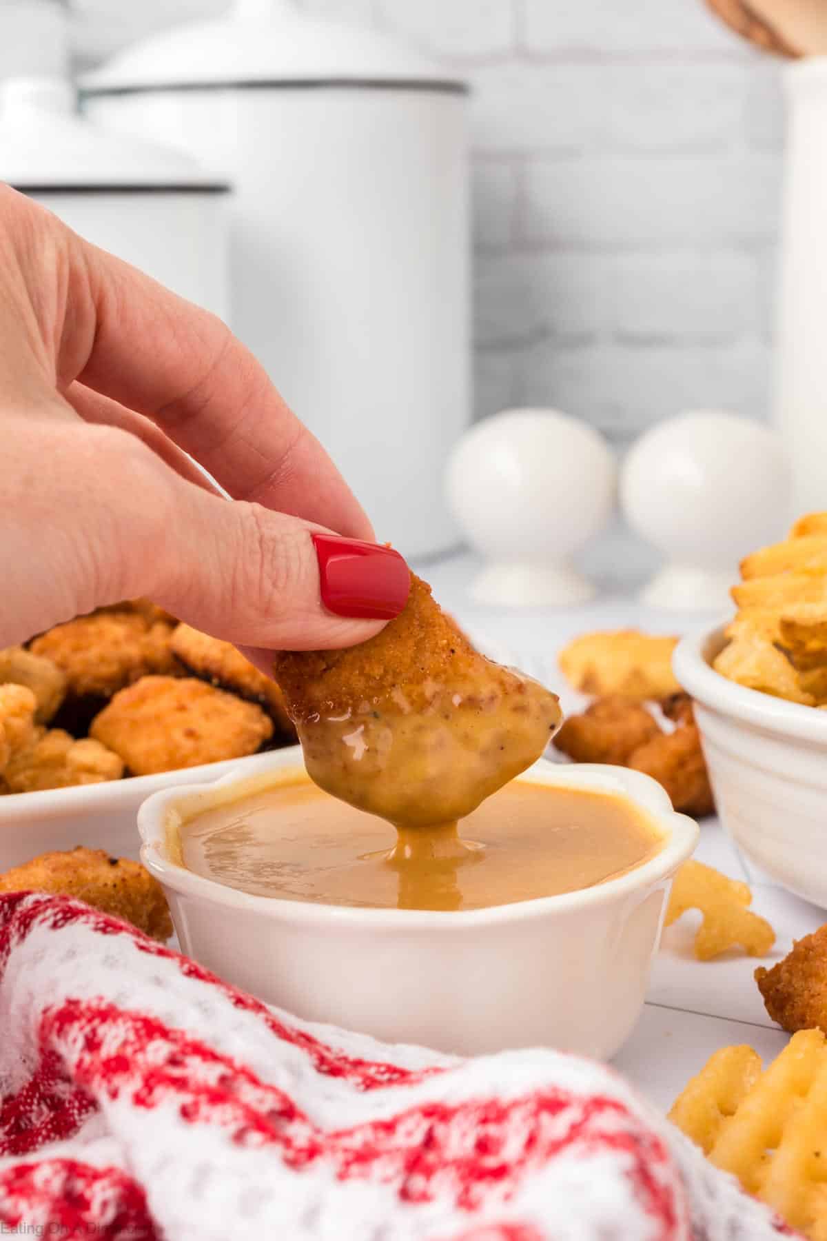 Dipping chicken nuggets in Chick Fil A Sauce in a bowl