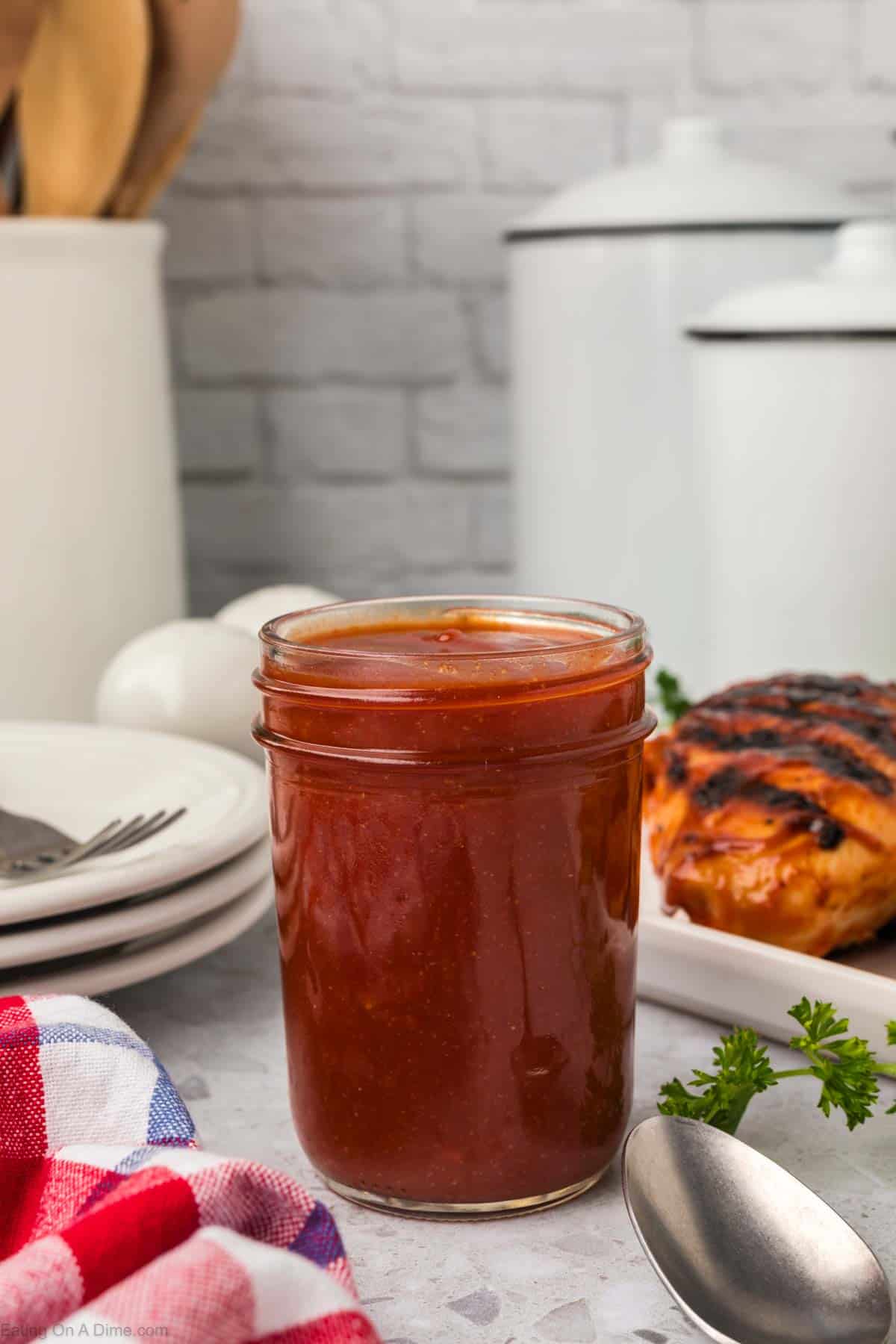 Mason jar of BBQ Sauce with a grilled chicken in the background