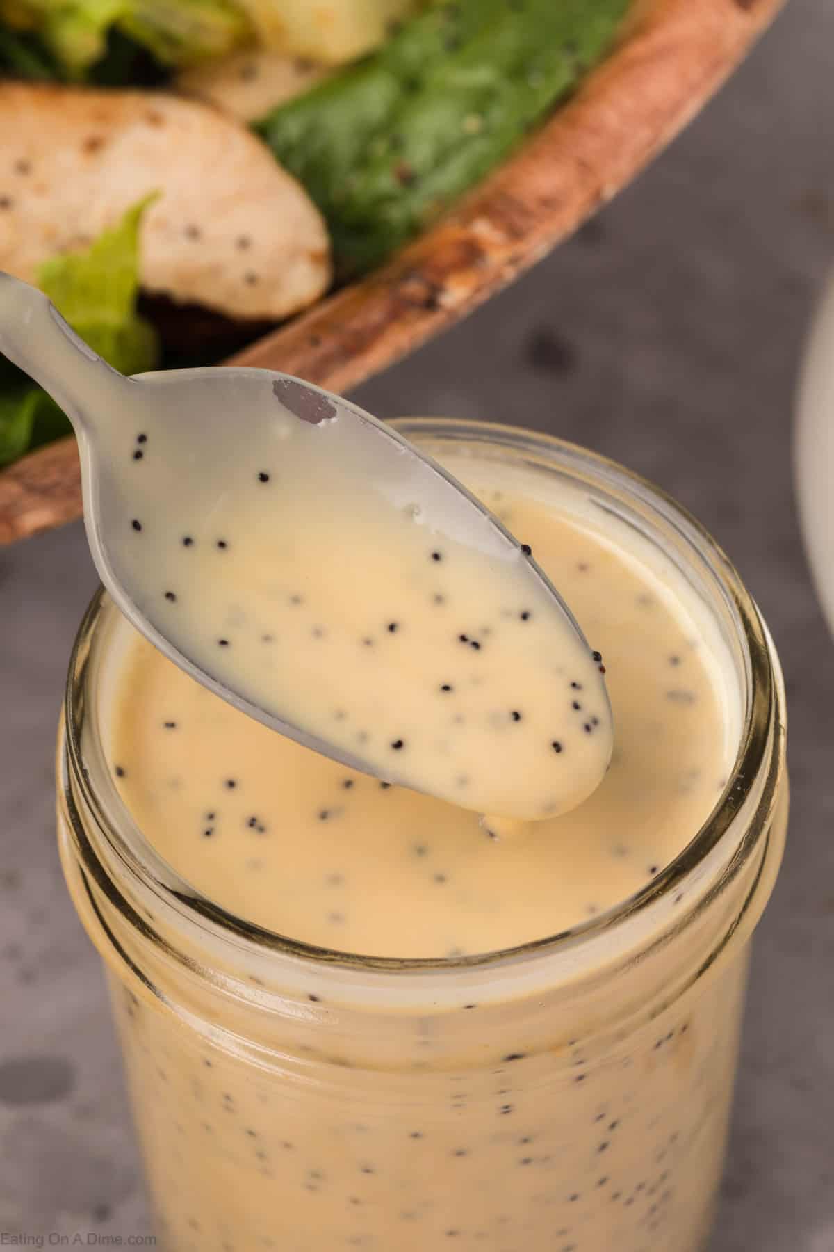 Poppyseed salad dressing in a mason jar with a small portion on a spoon