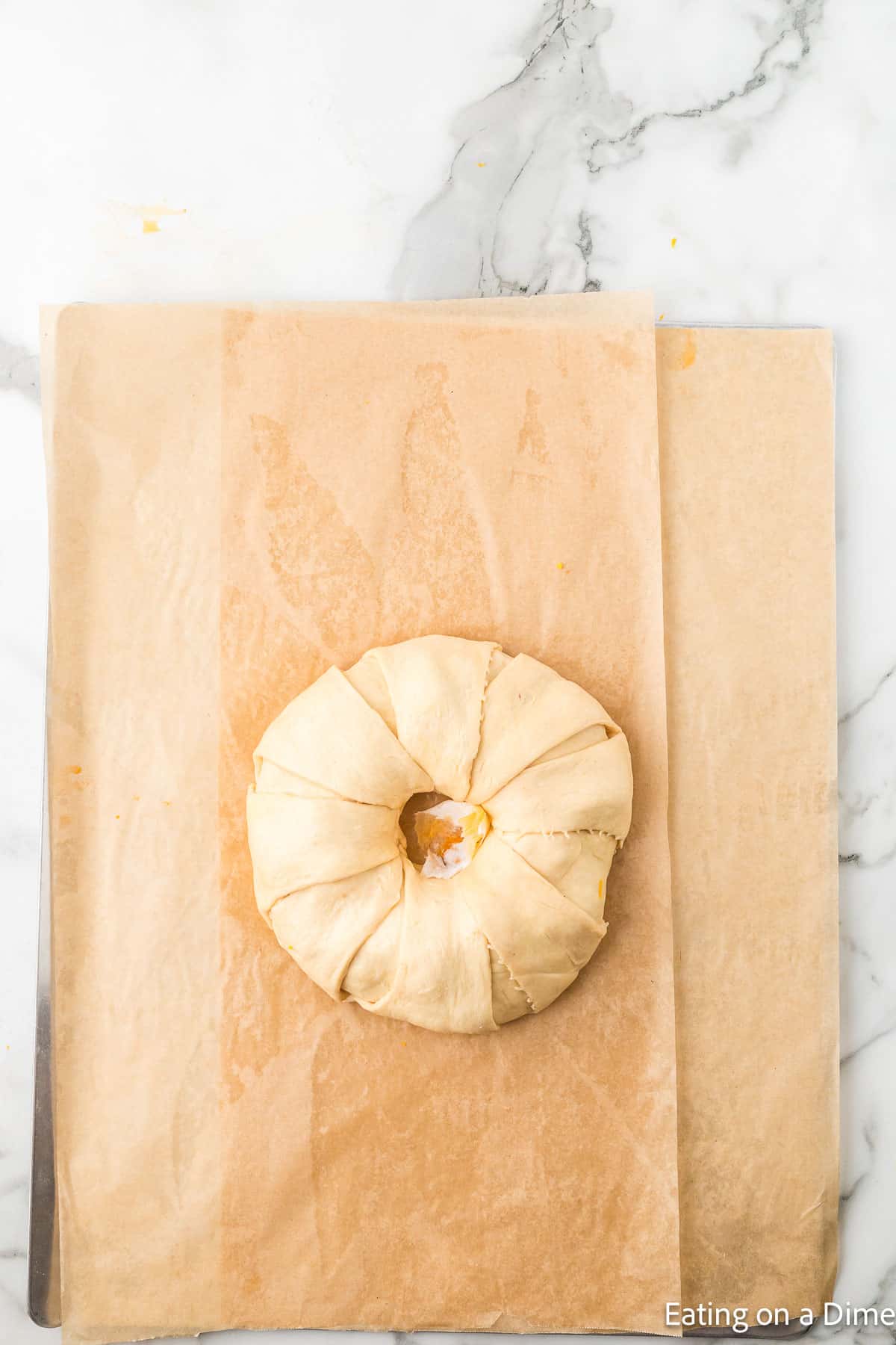 Uncooked crescent roll taco ring on parchment paper