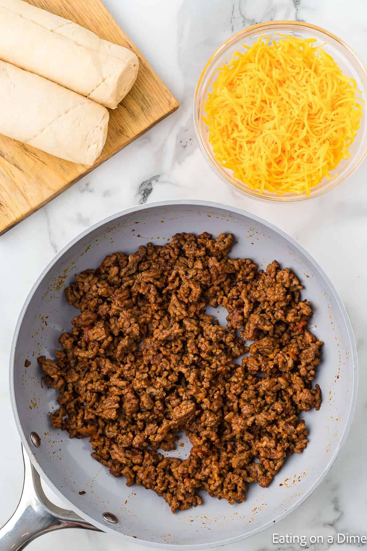 Taco seasoning mixed with cooked ground beef in a large skillet