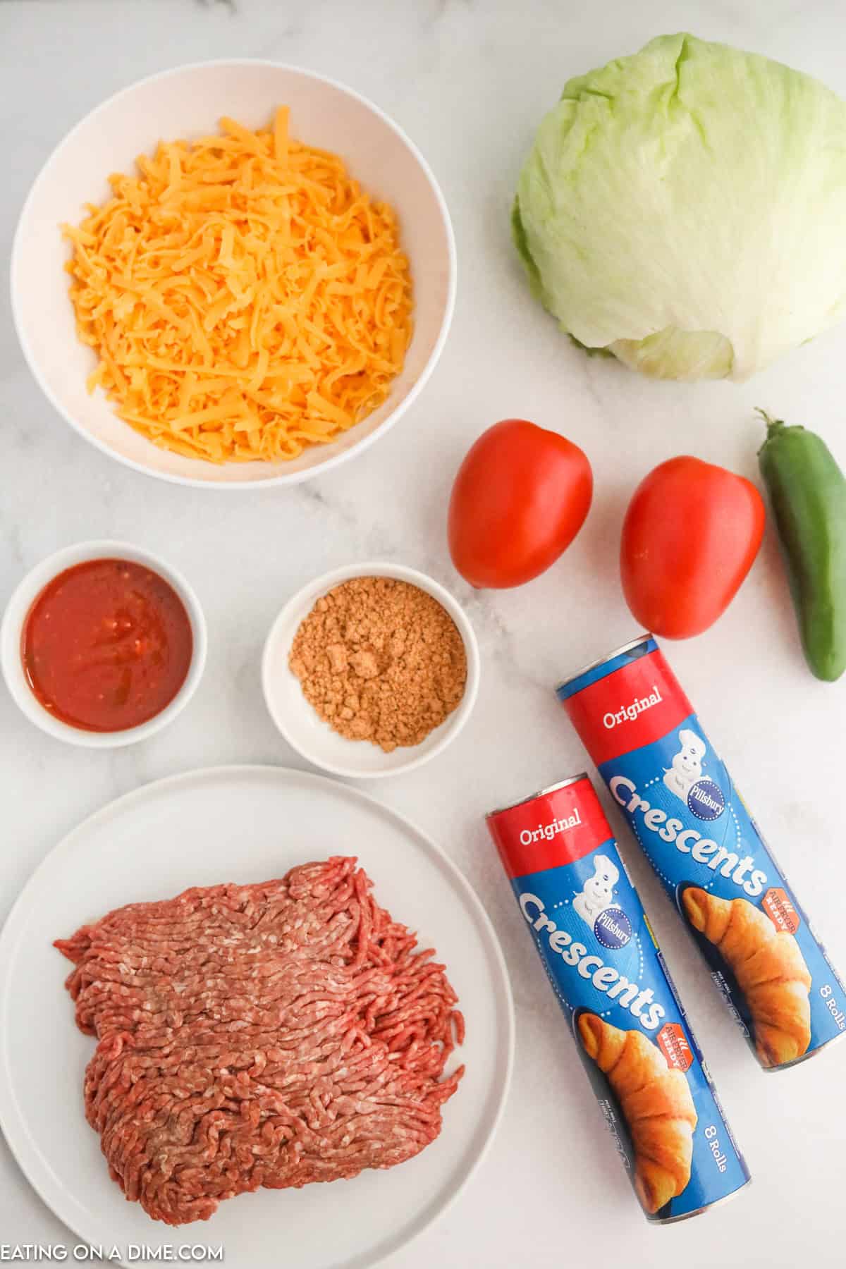 Ingredients to Make Crescent Taco Ring - Ground Beef, salsa, taco seasoning, cheese, crescent rolls, roma tomato, lettuce, jalapeno