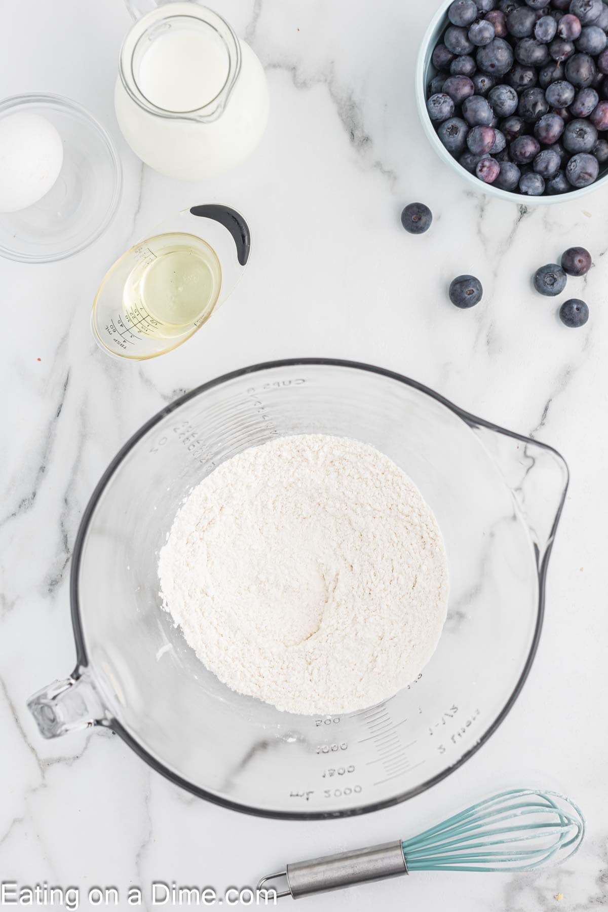 Placing the flour, salt and baking powder in a large measuring cup bowl. A blow of blueberries, oil and milk on the side