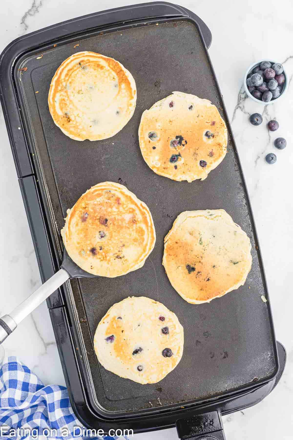 Cooked blueberry pancakes on a large skillet