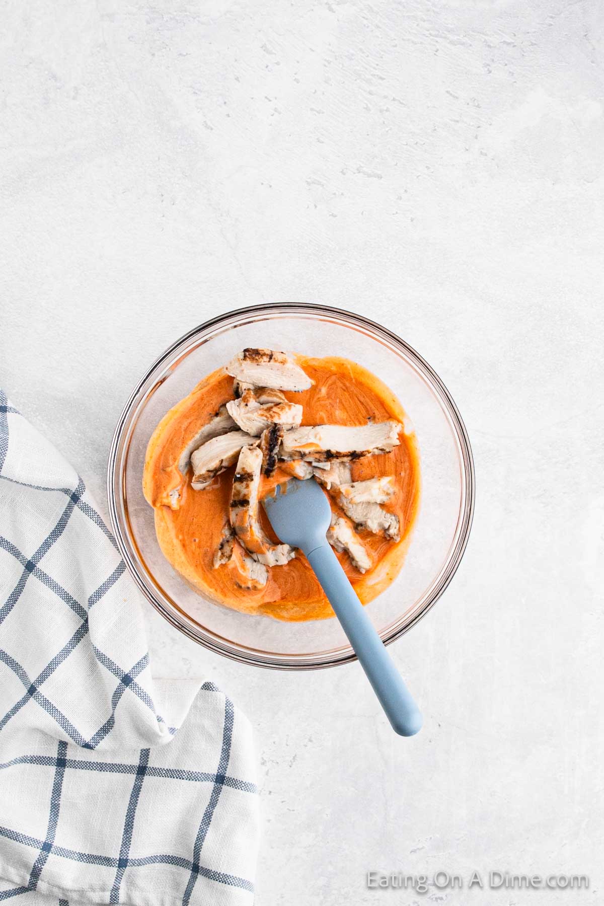 Buffalo Sauce mixture in a bowl topped with strips of grilled chicken 