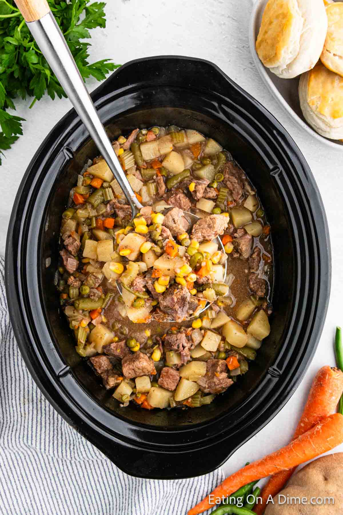Prepared Crock Pot beef Pot pie in the slow cooker with a serving on the ladle