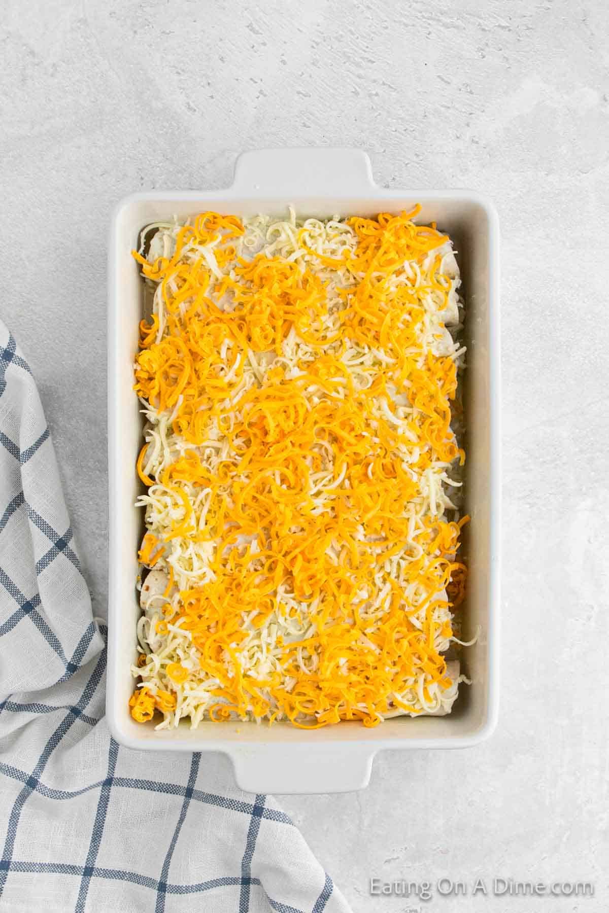 Shredded cheese tops the enchilada in a baking dish