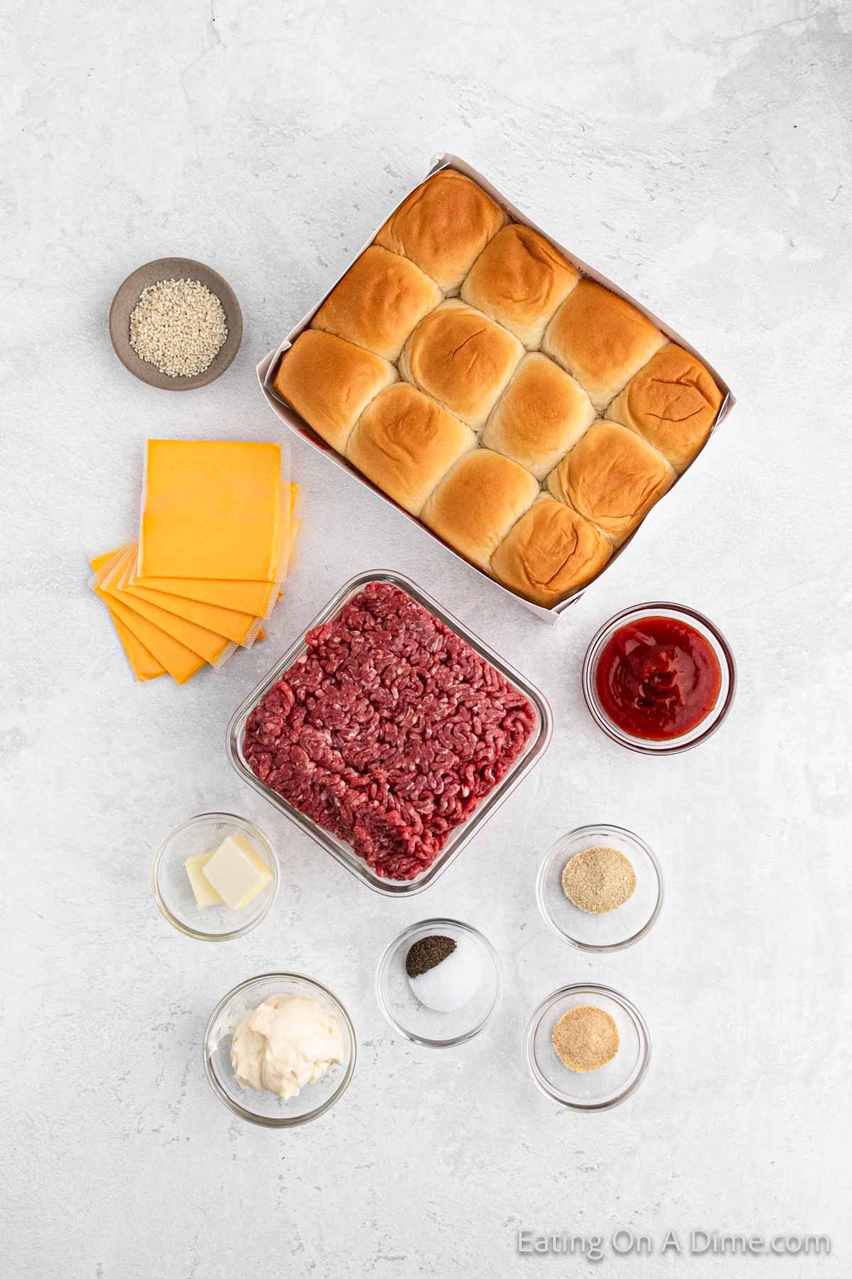 An overhead view of ingredients arranged for making sliders, including a tray of ground beef, cheese slices, ketchup, mayonnaise, seasonings, and butter—all set to create the perfect Hawaiian Roll Hamburger Recipe. The ingredients are neatly displayed on a light countertop.