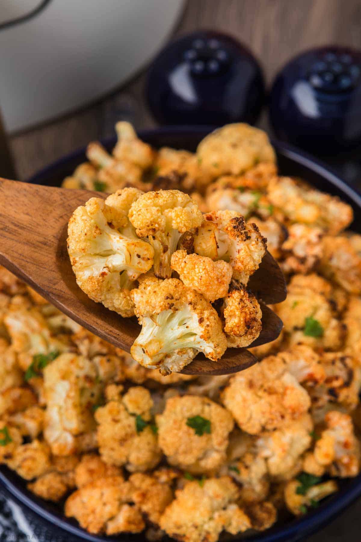 Air Fryer Cauliflower in a bowl with a serving on a wooden spoon
