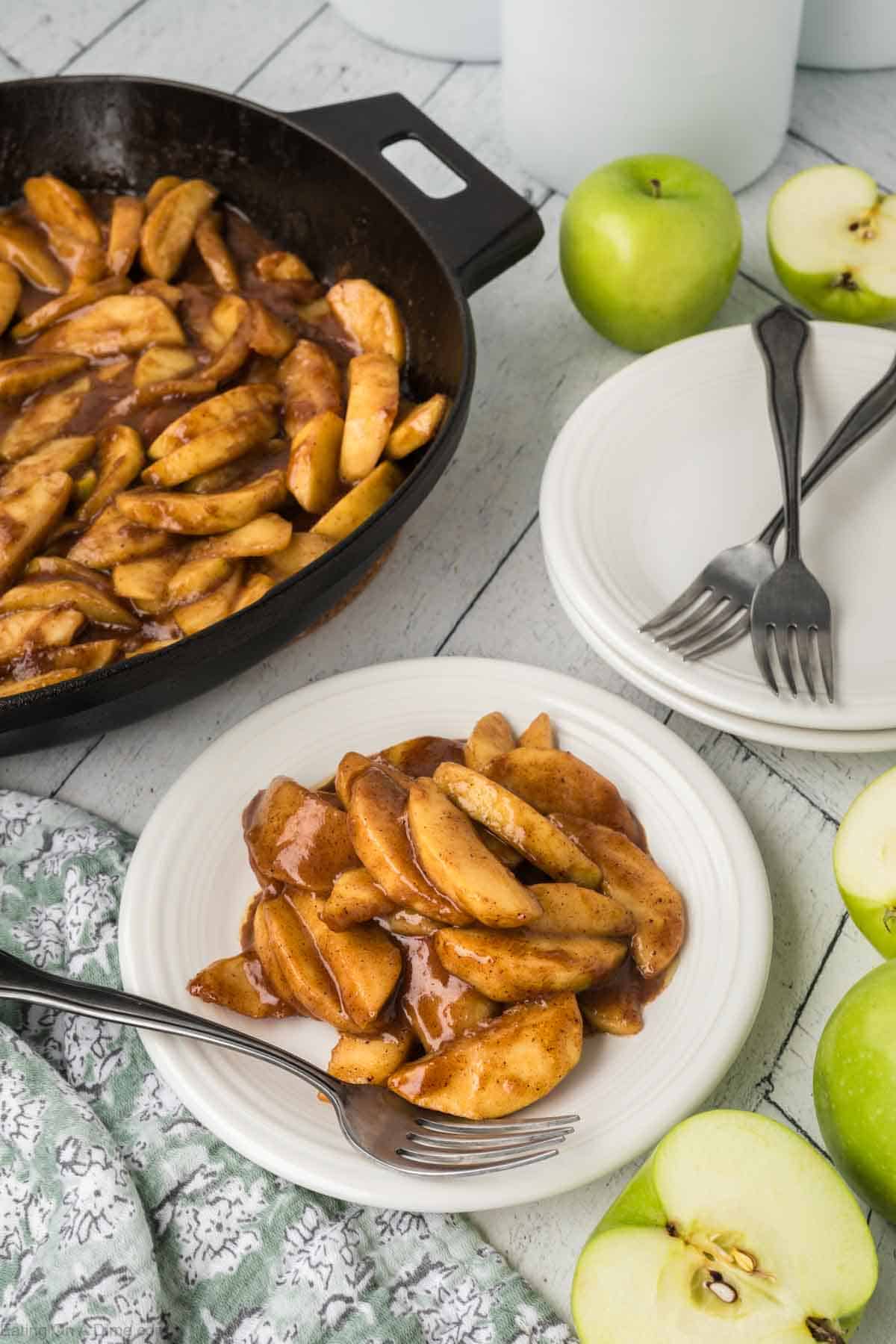 Fried Apples on a plate with a cast iron skillet full of fried apples