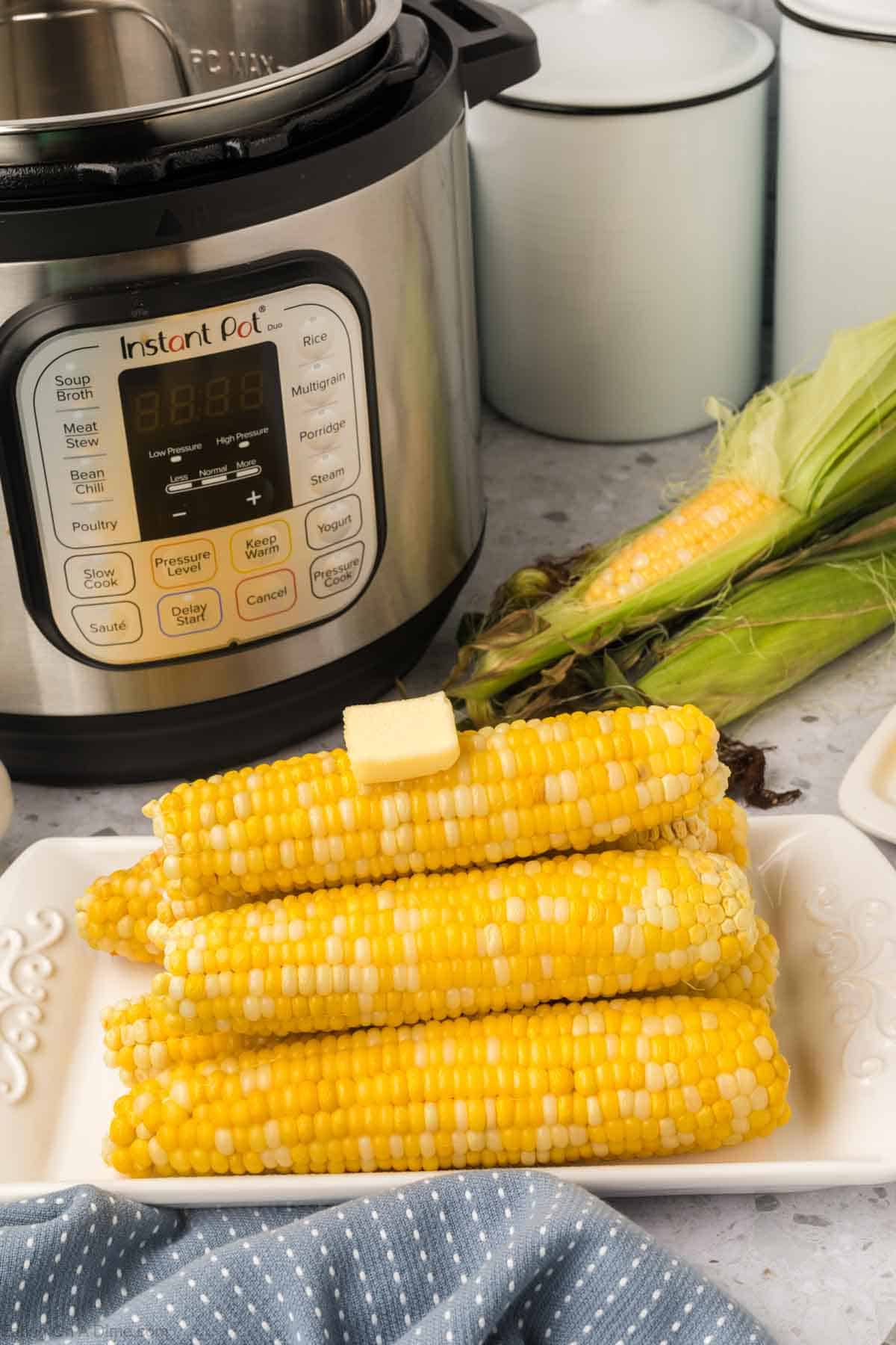 Corn on the cob stacked on the platter topped with melted butter