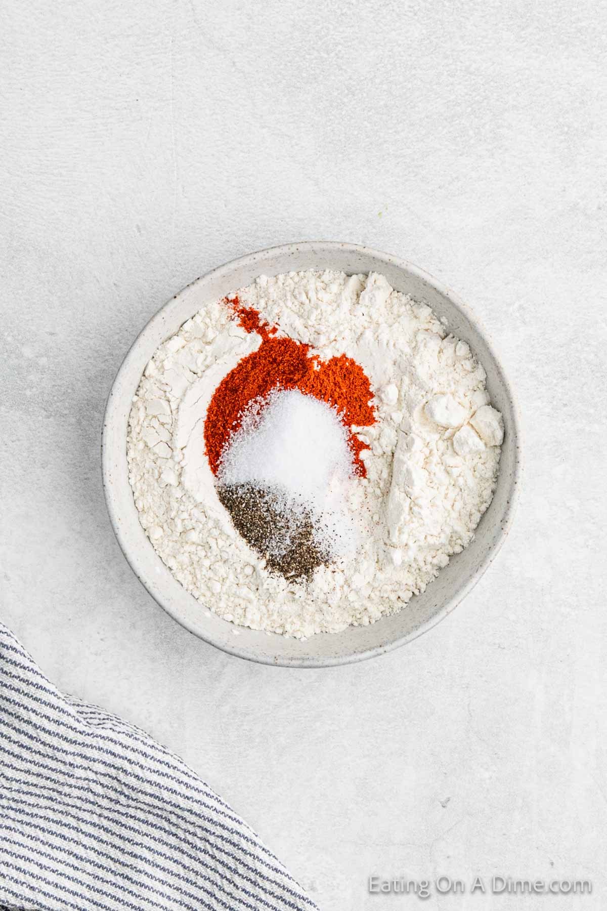 Flour and spices are mixed together in a bowl