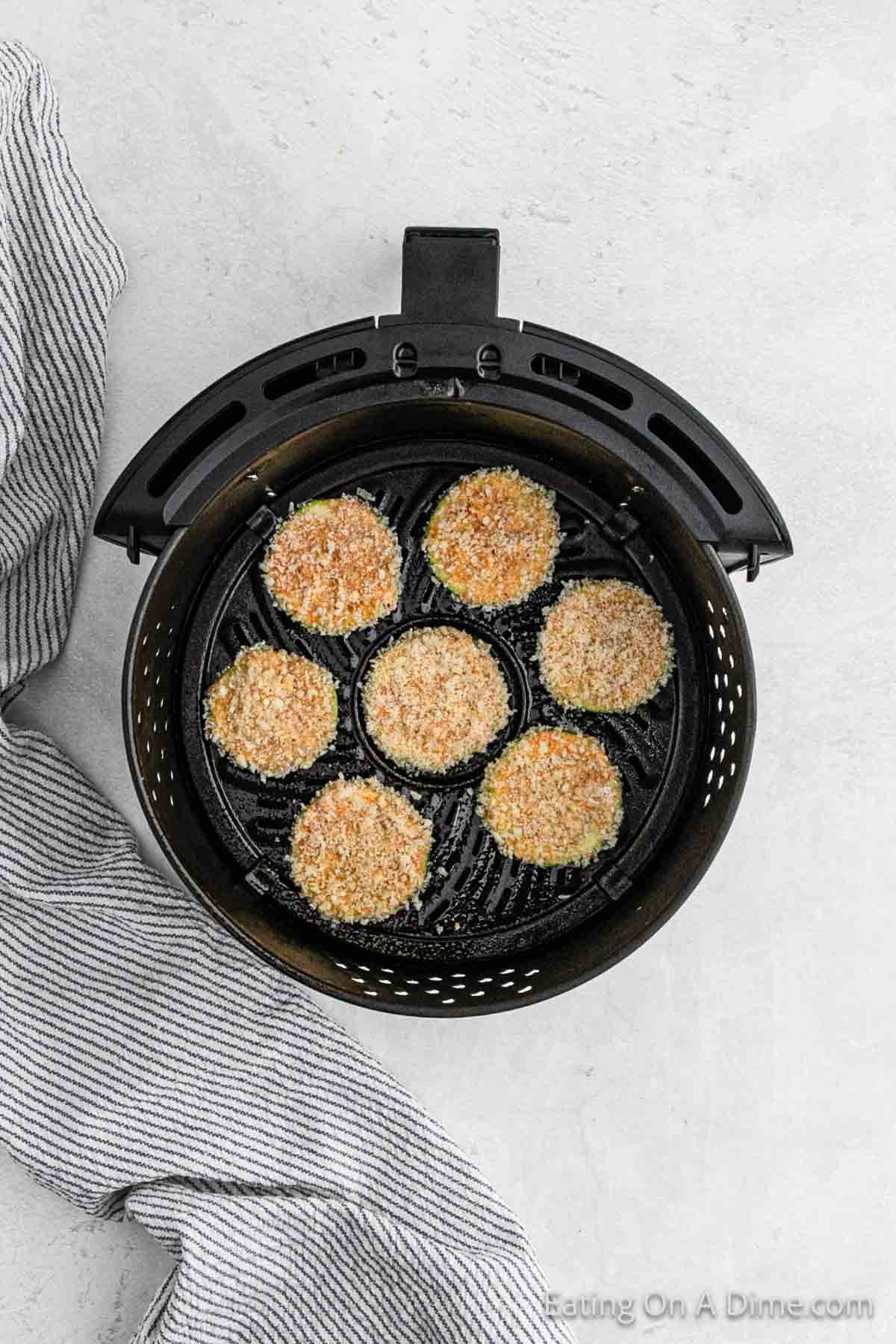 Placing the breaded zucchini slices in the air fryer basket