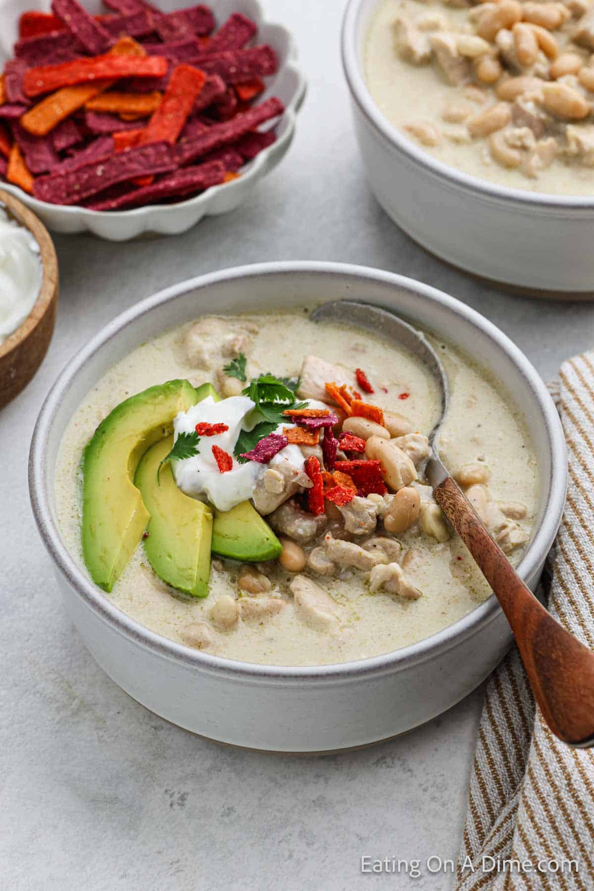 Bowl of Chicken Enchilada Soup topped with slice avocado, sour cream, cilantro and tortilla chips