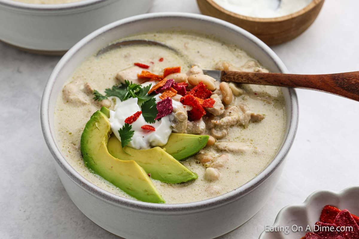 Bowl of Chicken Enchilada Soup topped with slice avocado, sour cream and cilantro