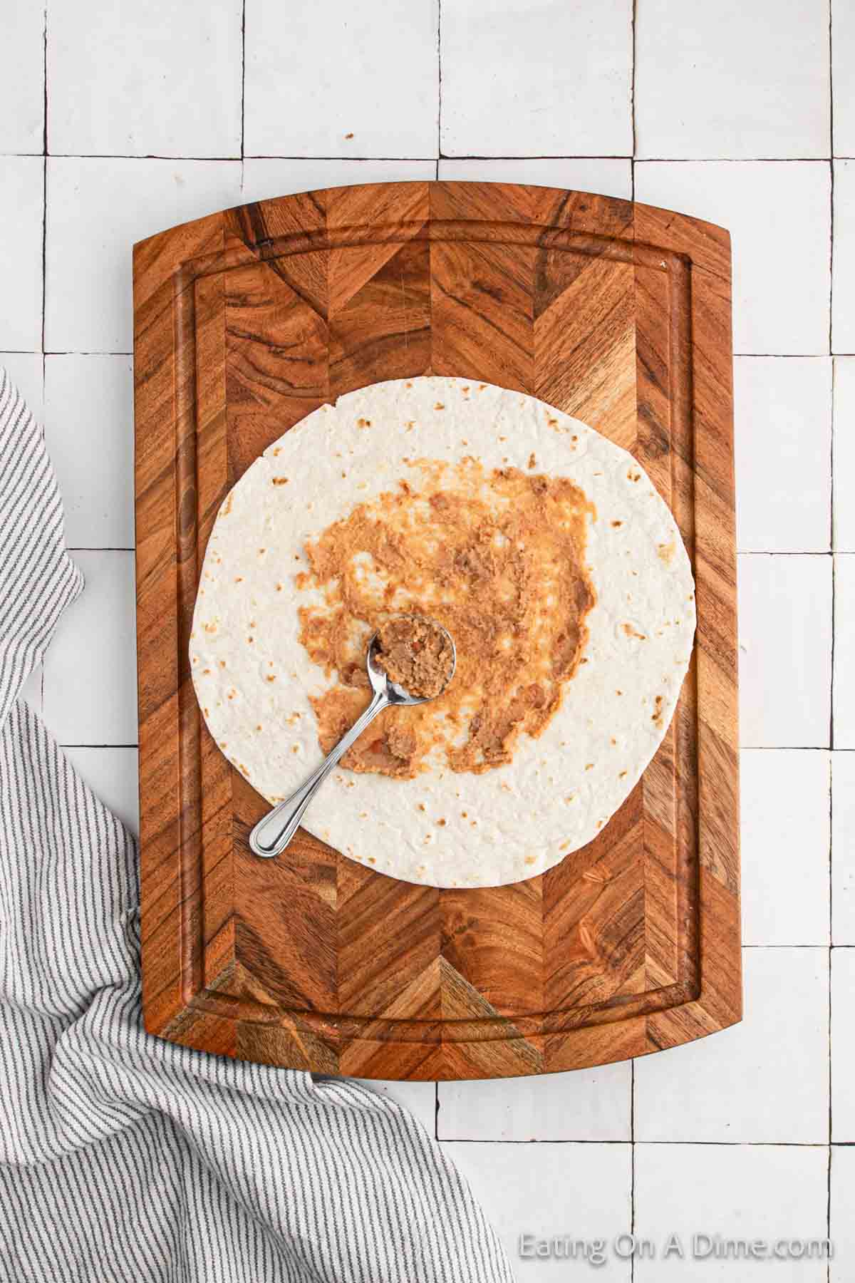 Spreading refried beans on a tortilla