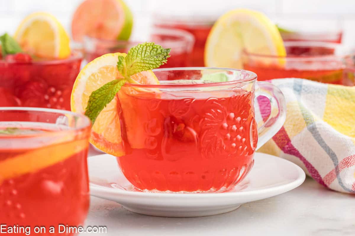 Clear glass mugs with punch filled with a side of lemon slices and fresh mint