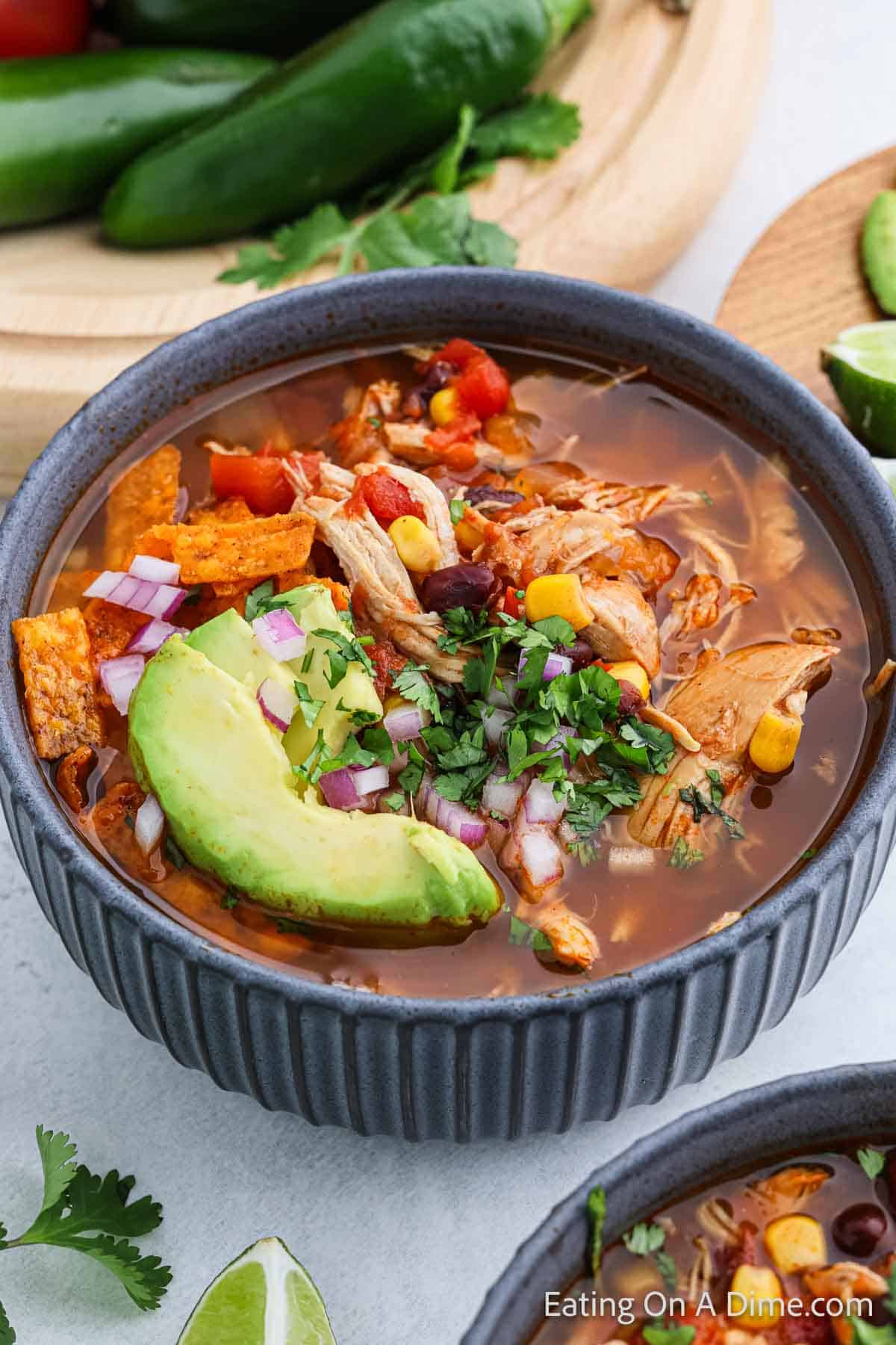 Bowl of Chicken Tortilla Soup topped with slice avocado, red onions and cilantro