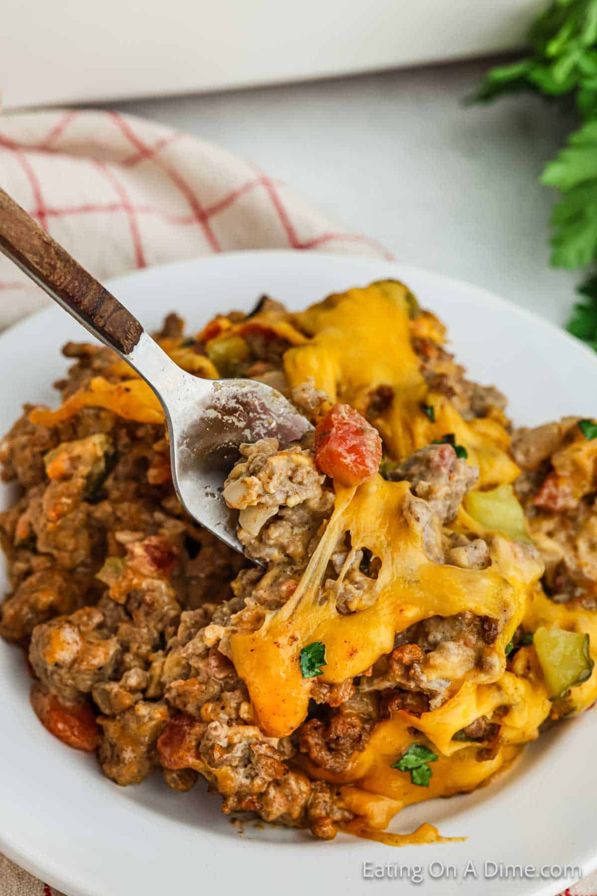 A serving of cheeseburger casserole on a plate with a bite on a fork