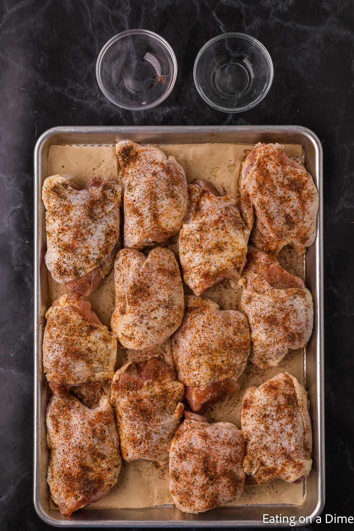 Seasoned Chicken Thighs on a baking sheet lined with parchment paper