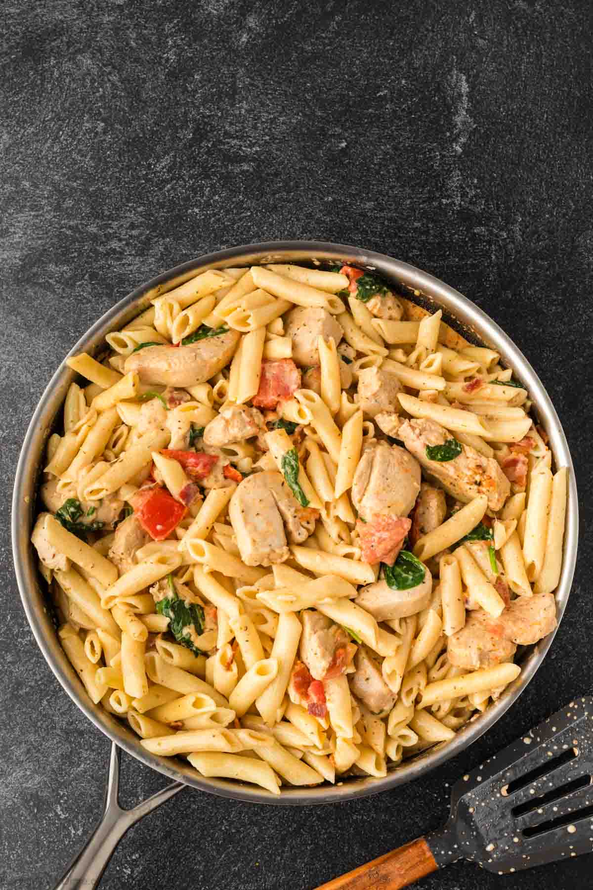 Pasta added to the chicken mixture in a skillet