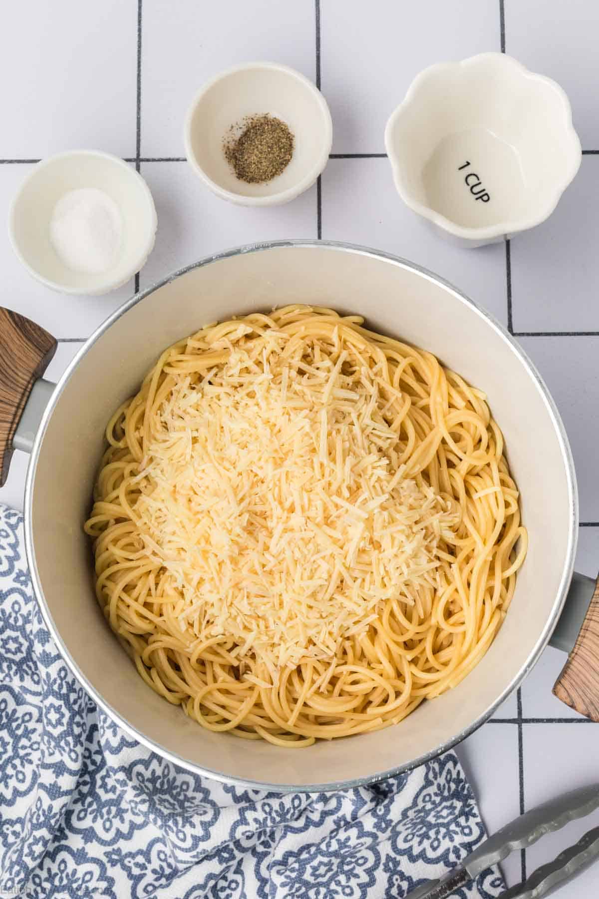 Topping the pasta with shredded parmesan cheese