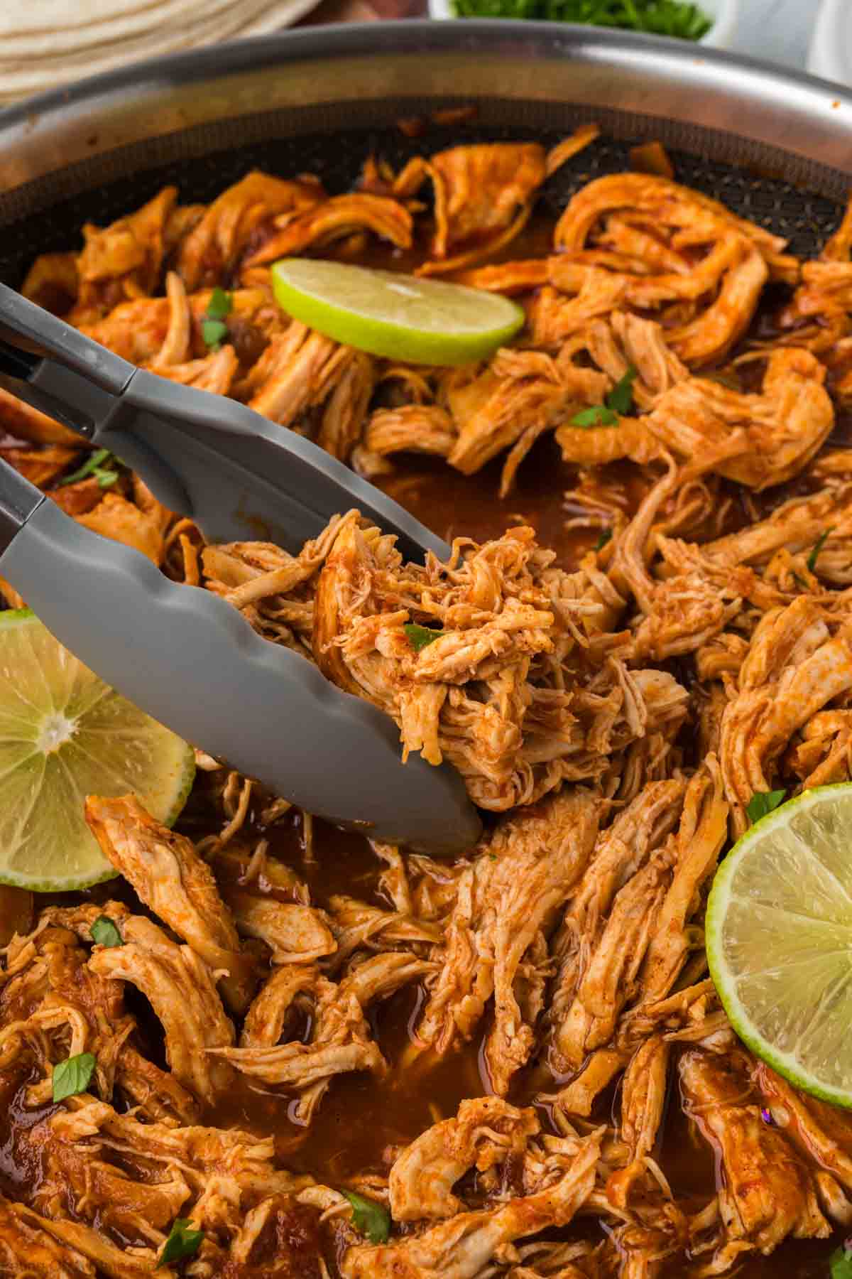 Mexican Shredded chicken with tongs topped with fresh lime