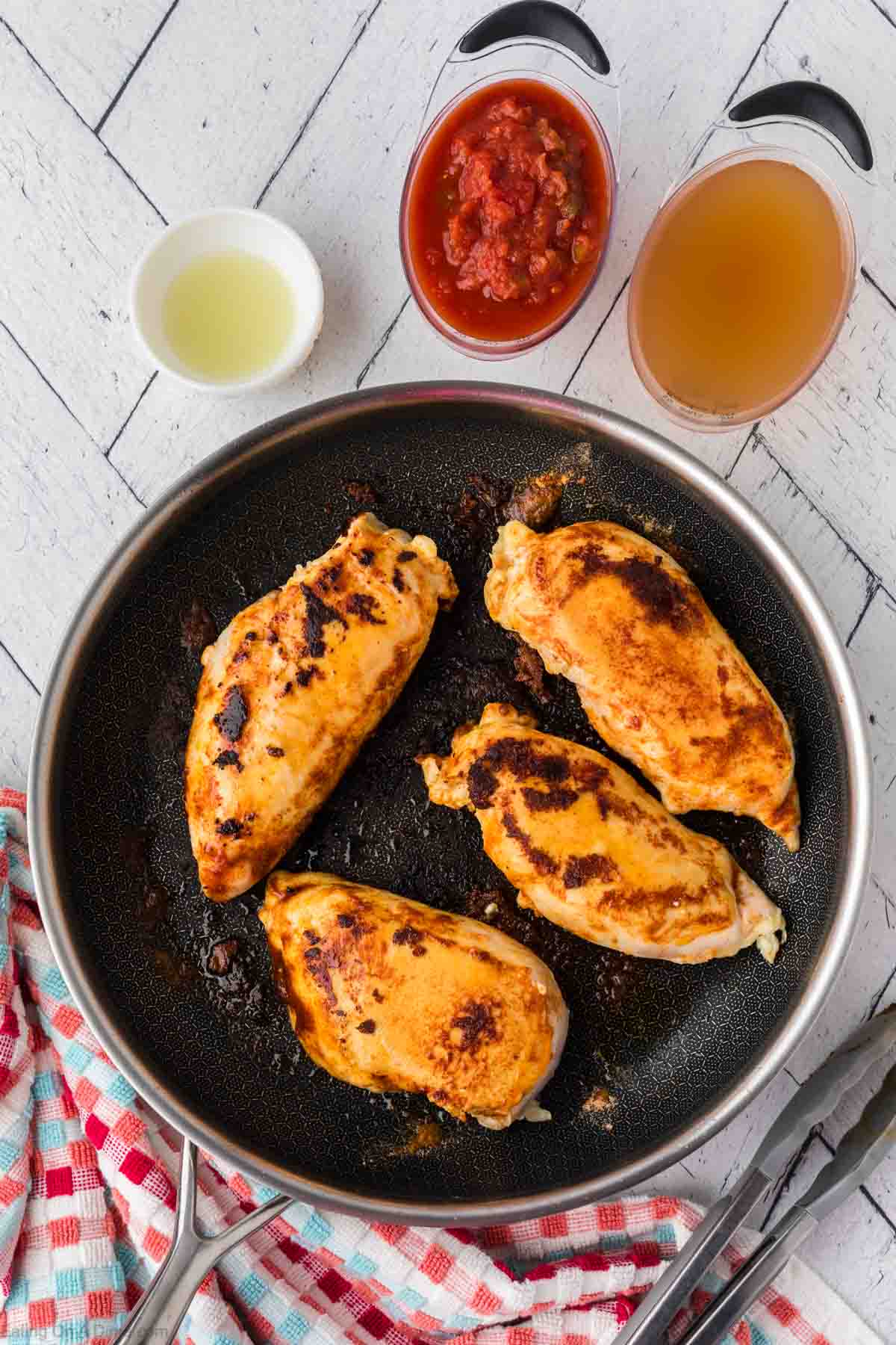 Browned chicken breast in the skillet with small bowls of salsa and broth on the side