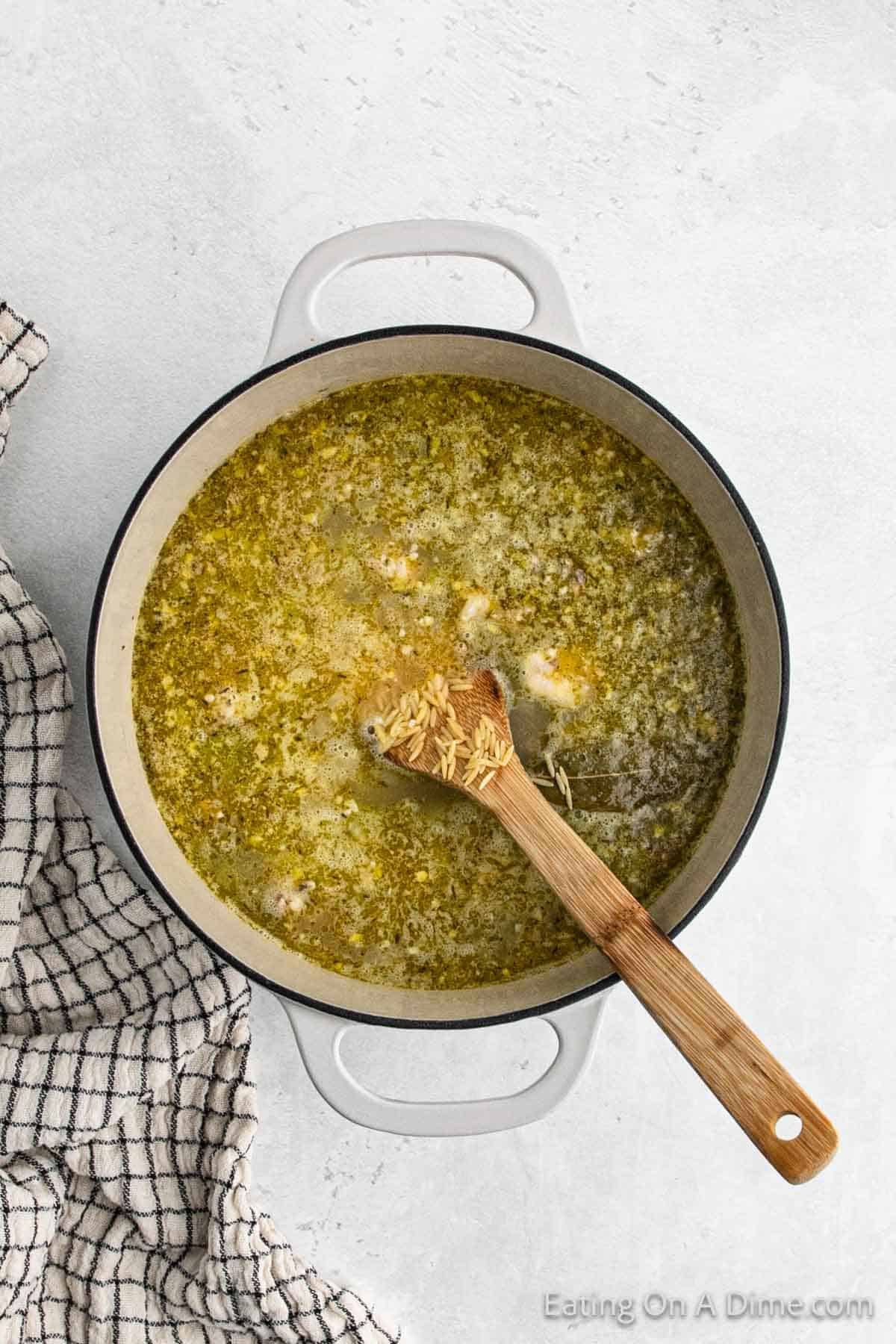 Mixing in the Orzo to the broth with the chicken and vegetables. 