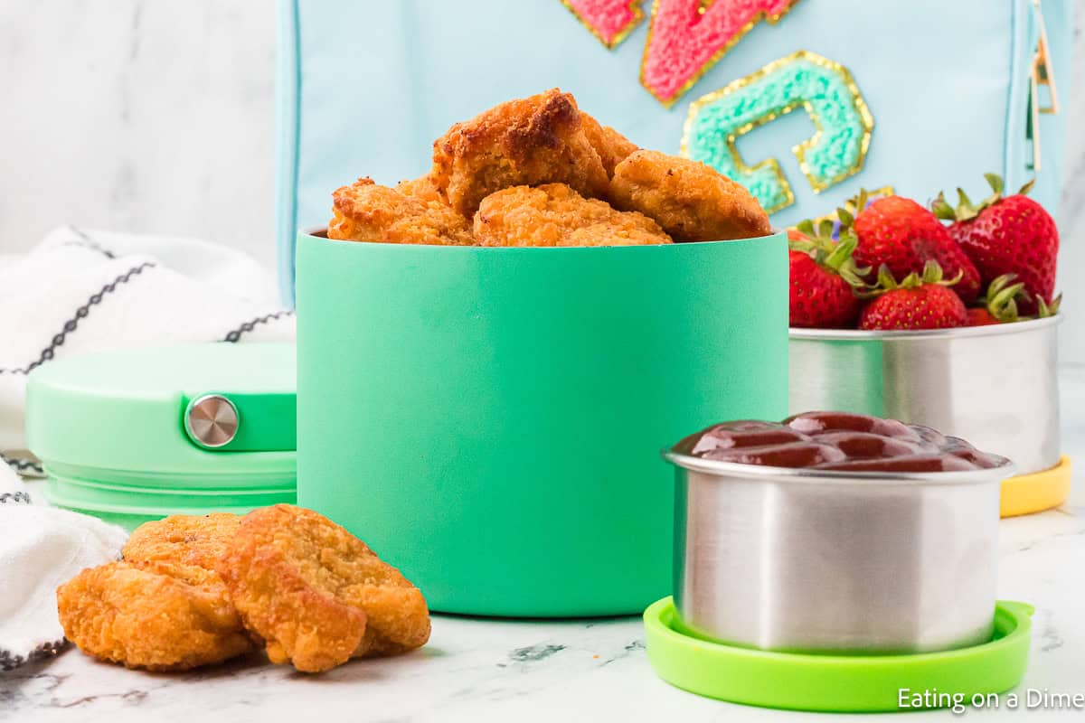 Lunch Container with chicken nuggets with a container with ketchup and fresh strawberries